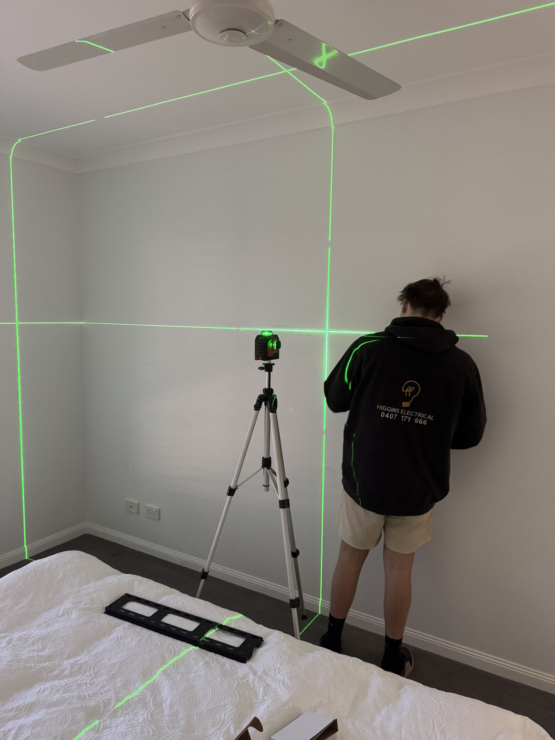 Person Using a Green Laser Level on a Tripod — Higgins Electrical in Narangba, QLD