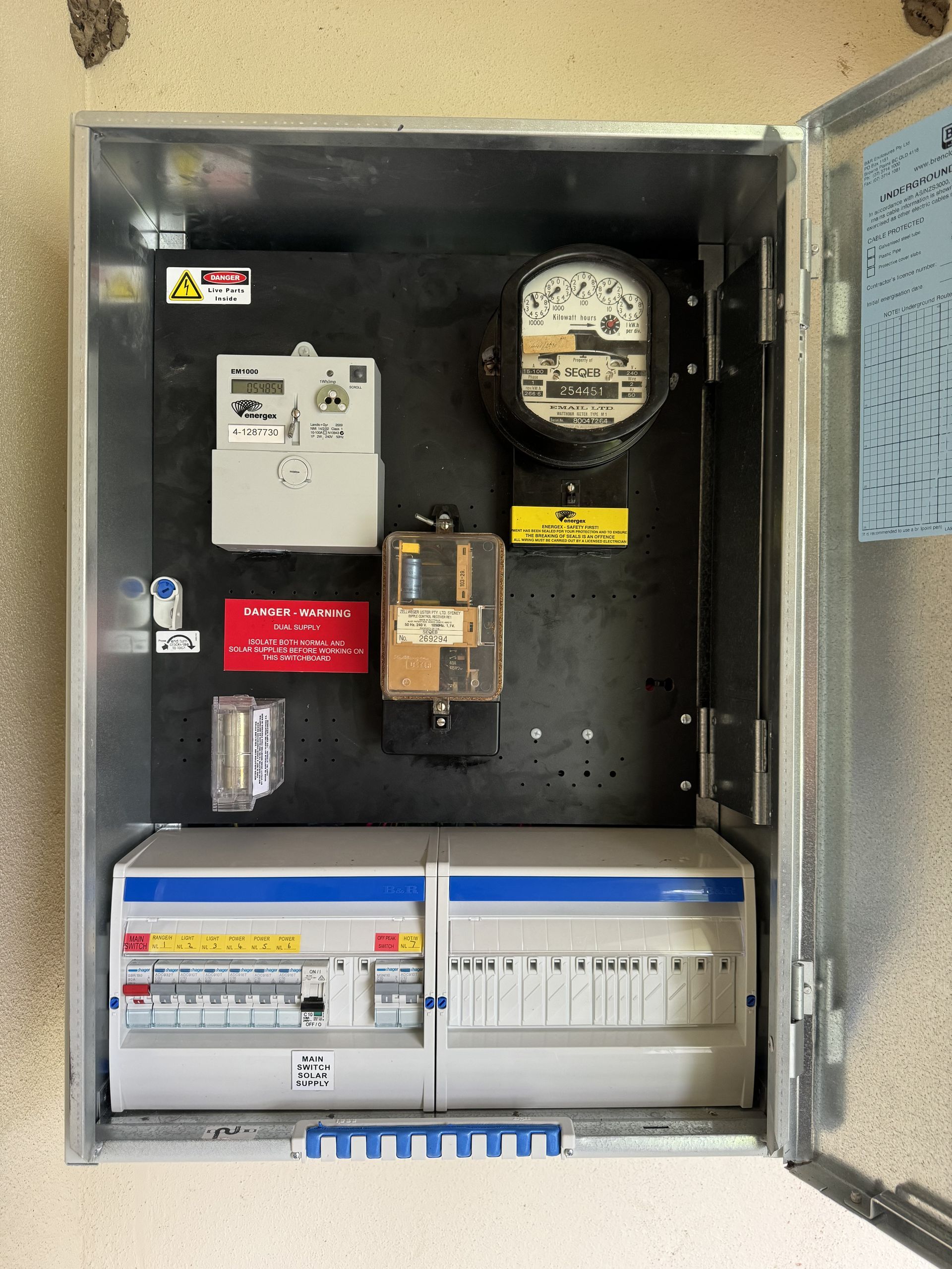 Metal electrical box with meters and circuit breakers on a wall — Higgins Electrical in Beerwah, QLD