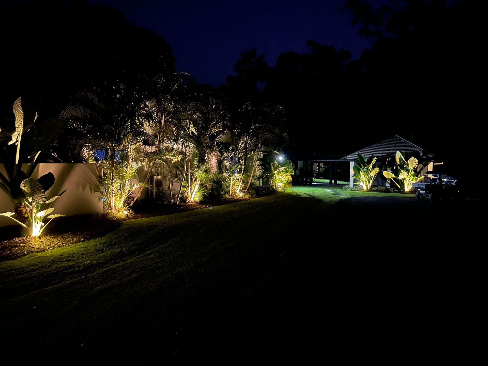 A House at Night, Lit With Yellow Lights, With a Carport and Palm Trees — Higgins Electrical in Bribie Island, QLD