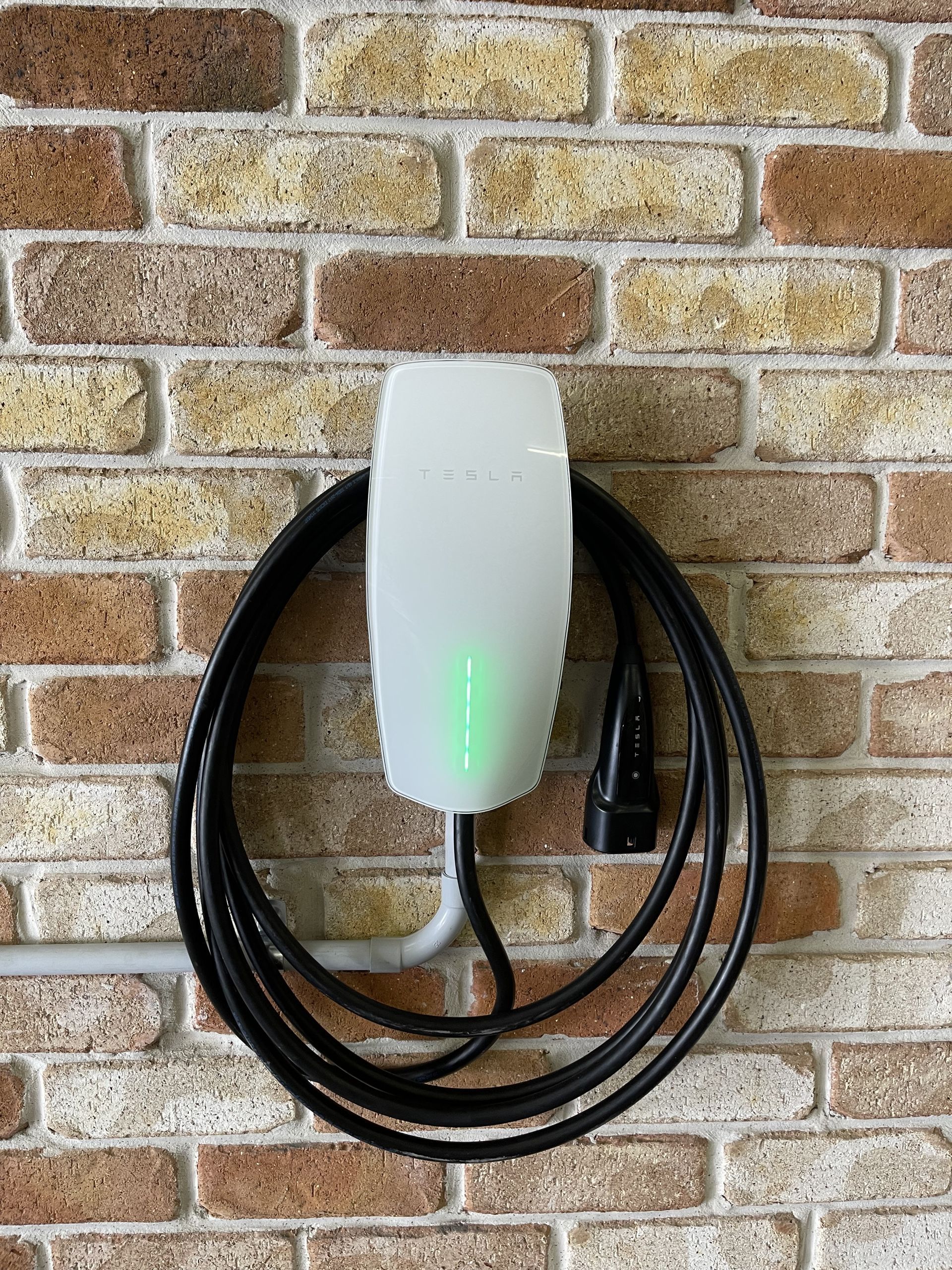 White EV Charger on Brick Wall, Cable Coiled — Higgins Electrical in Beerwah, QLD