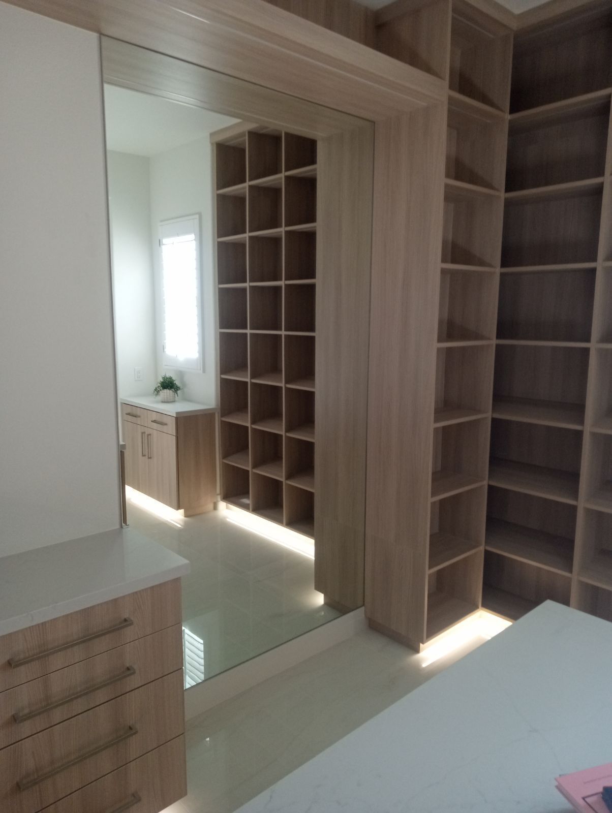 Built-in wooden closet with mirrored doors and open shelving in a bright bedroom