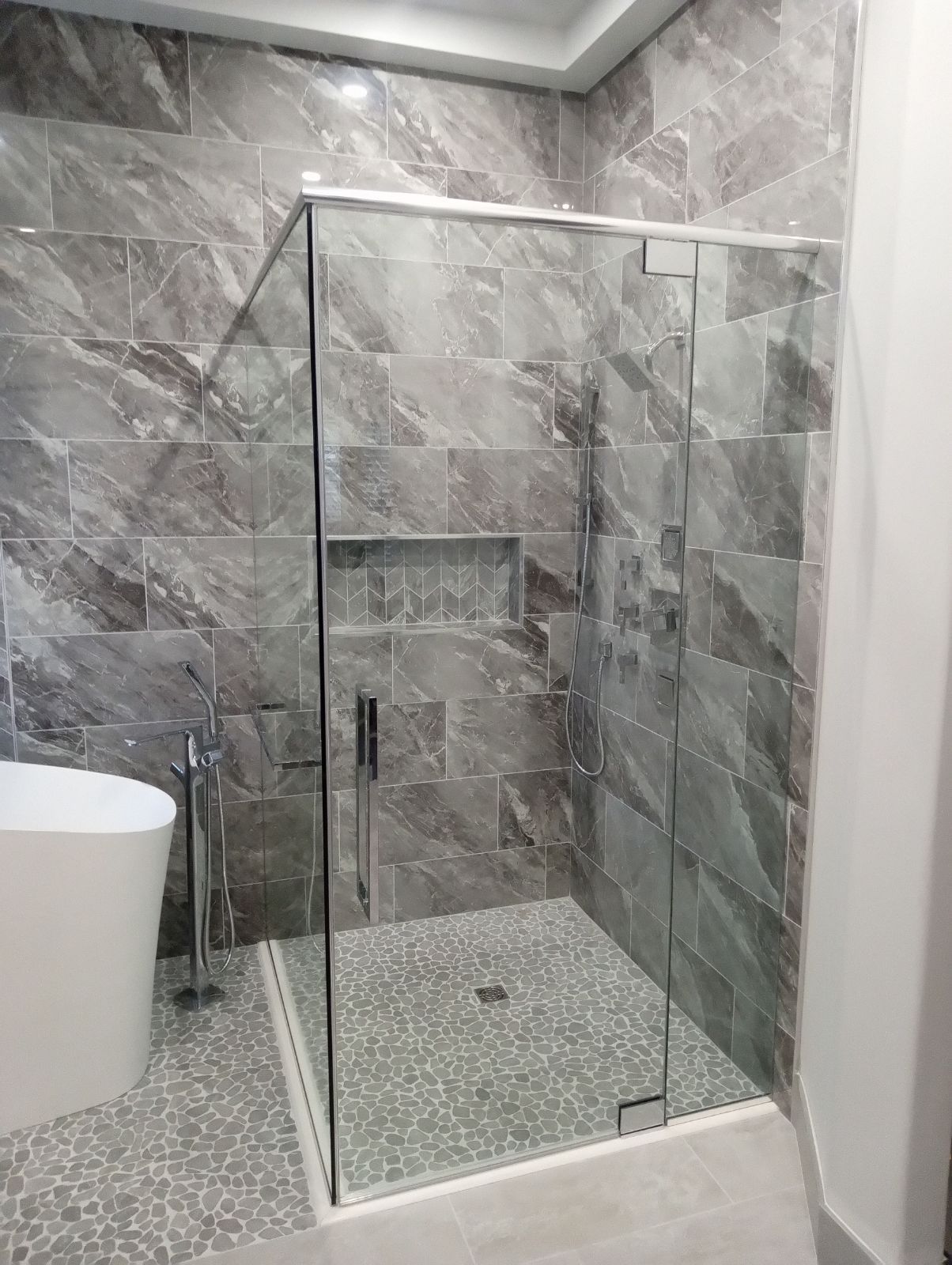 Modern tiled bathroom with a glass walk-in shower and pebble shower floor