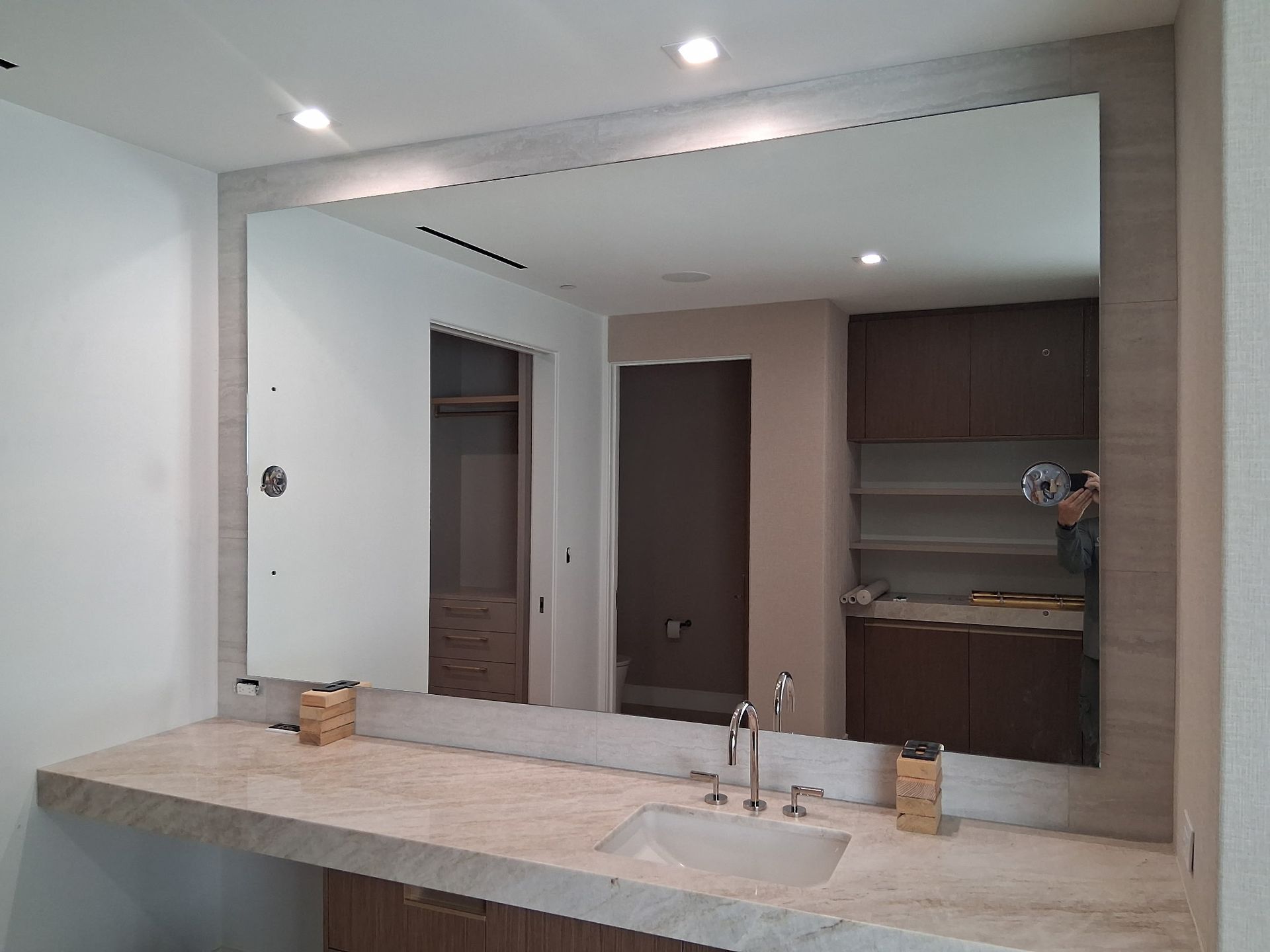 Modern bathroom with large mirror, double sink vanity, and brown cabinets under recessed lights