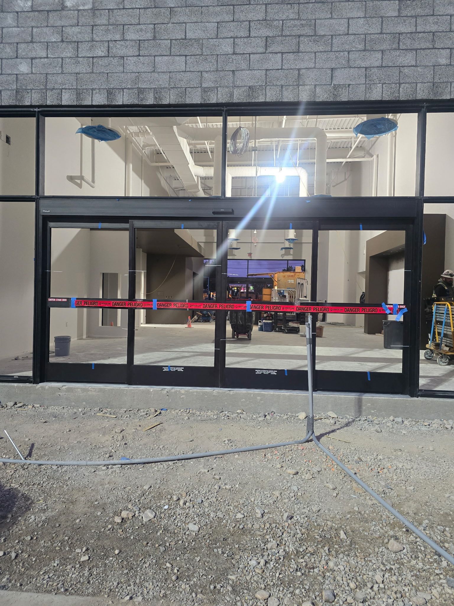 Closed storefront with glass doors and red caution tape across the entrance