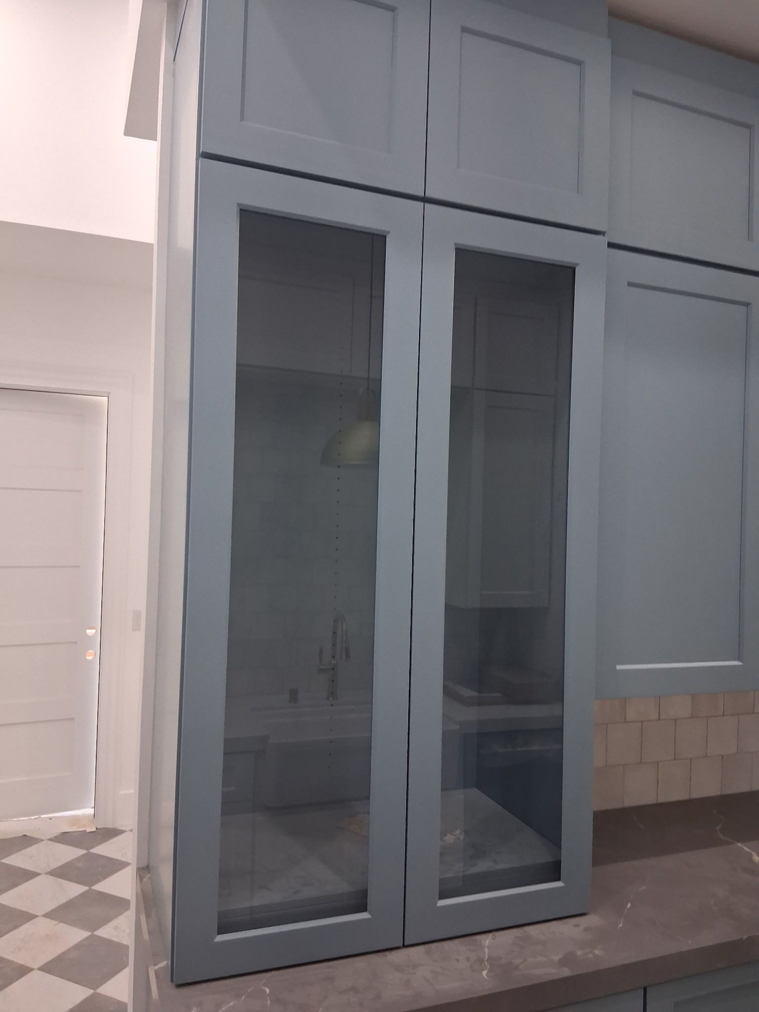 Gray built-in cabinet with glass doors in a modern kitchen or hallway.
