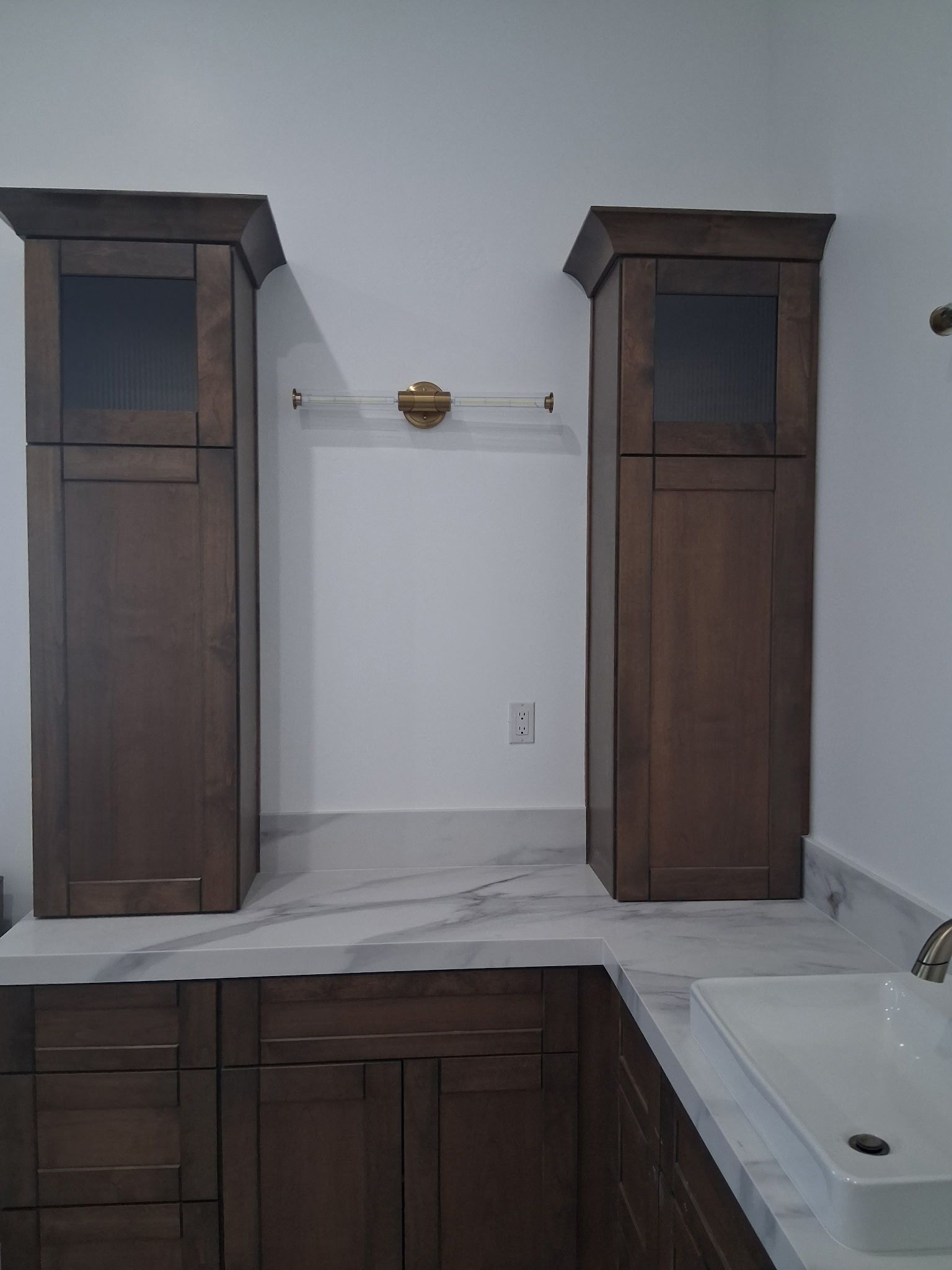 Bathroom with two tall wooden cabinets, white vanity, and a sink under renovation.