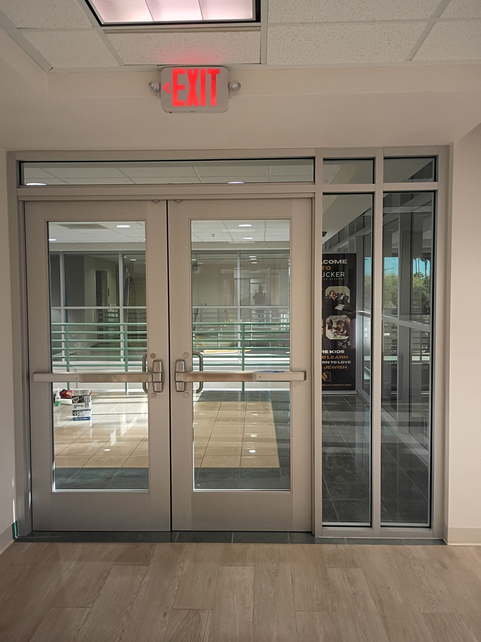 Glass double doors in a hallway with a red EXIT sign above them.