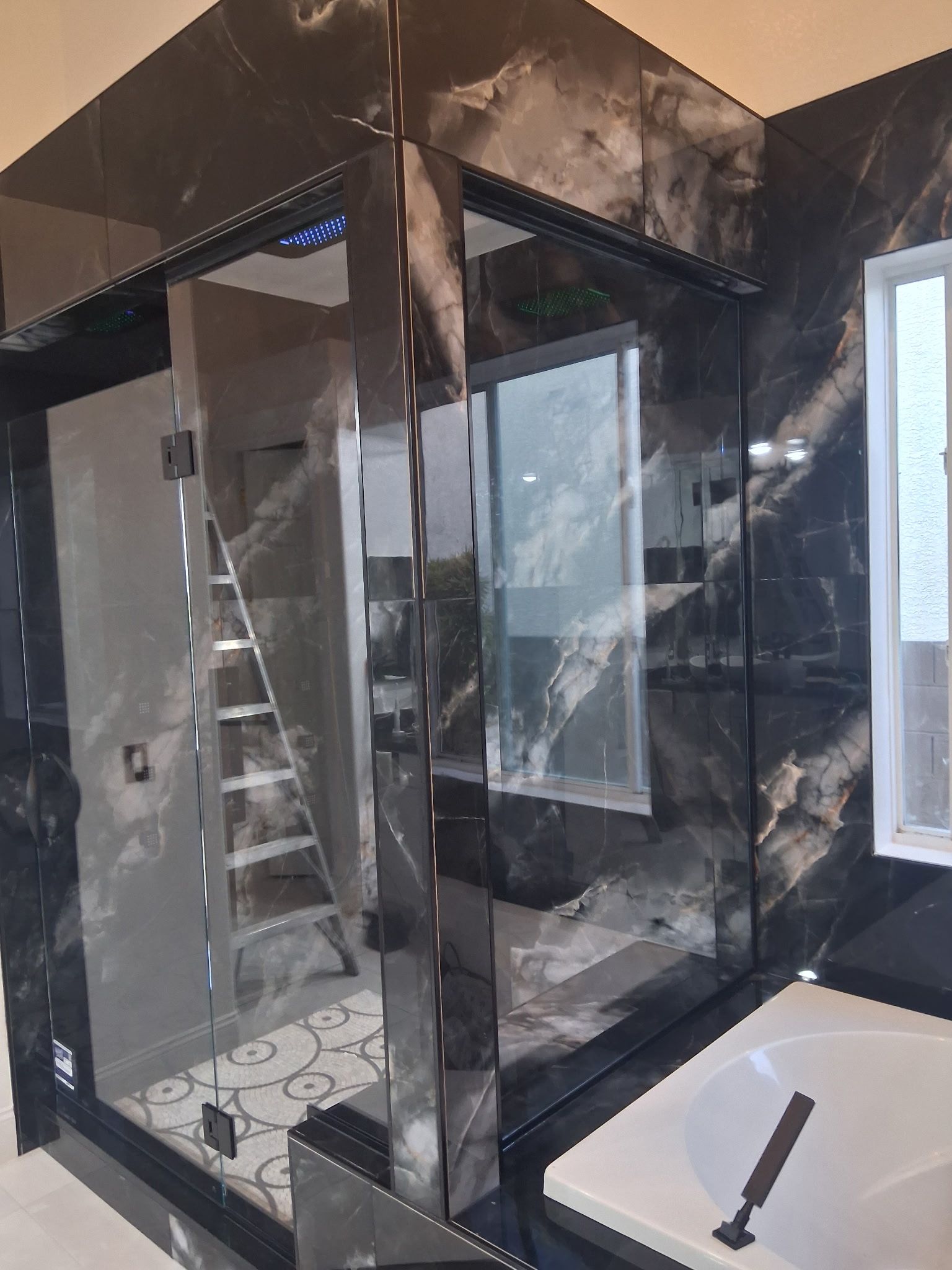 Damaged glass shower enclosure with black smoke stains in a bathroom.