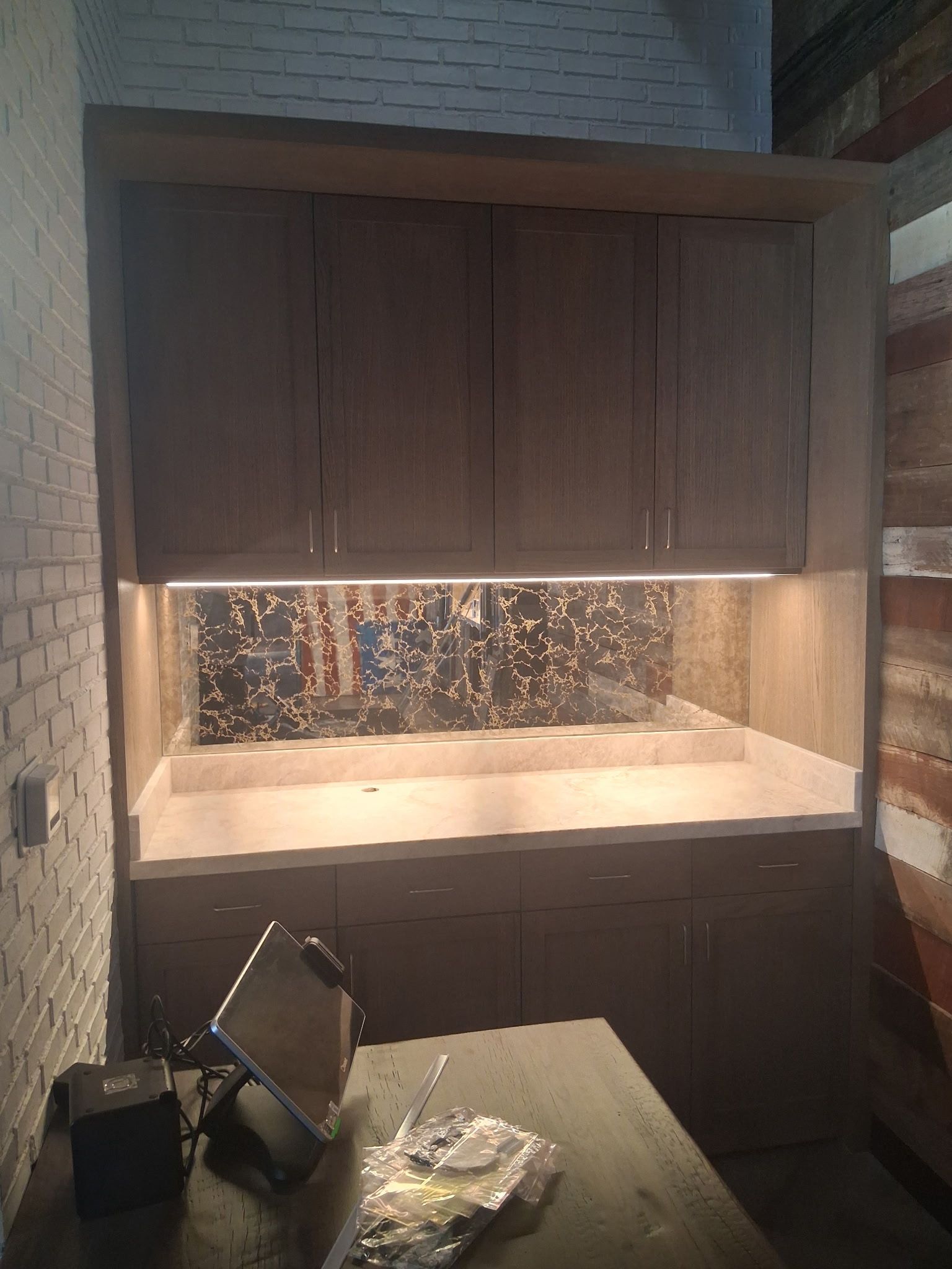 Dimly lit built-in cabinet with under-cabinet lighting and dark wood doors above a countertop