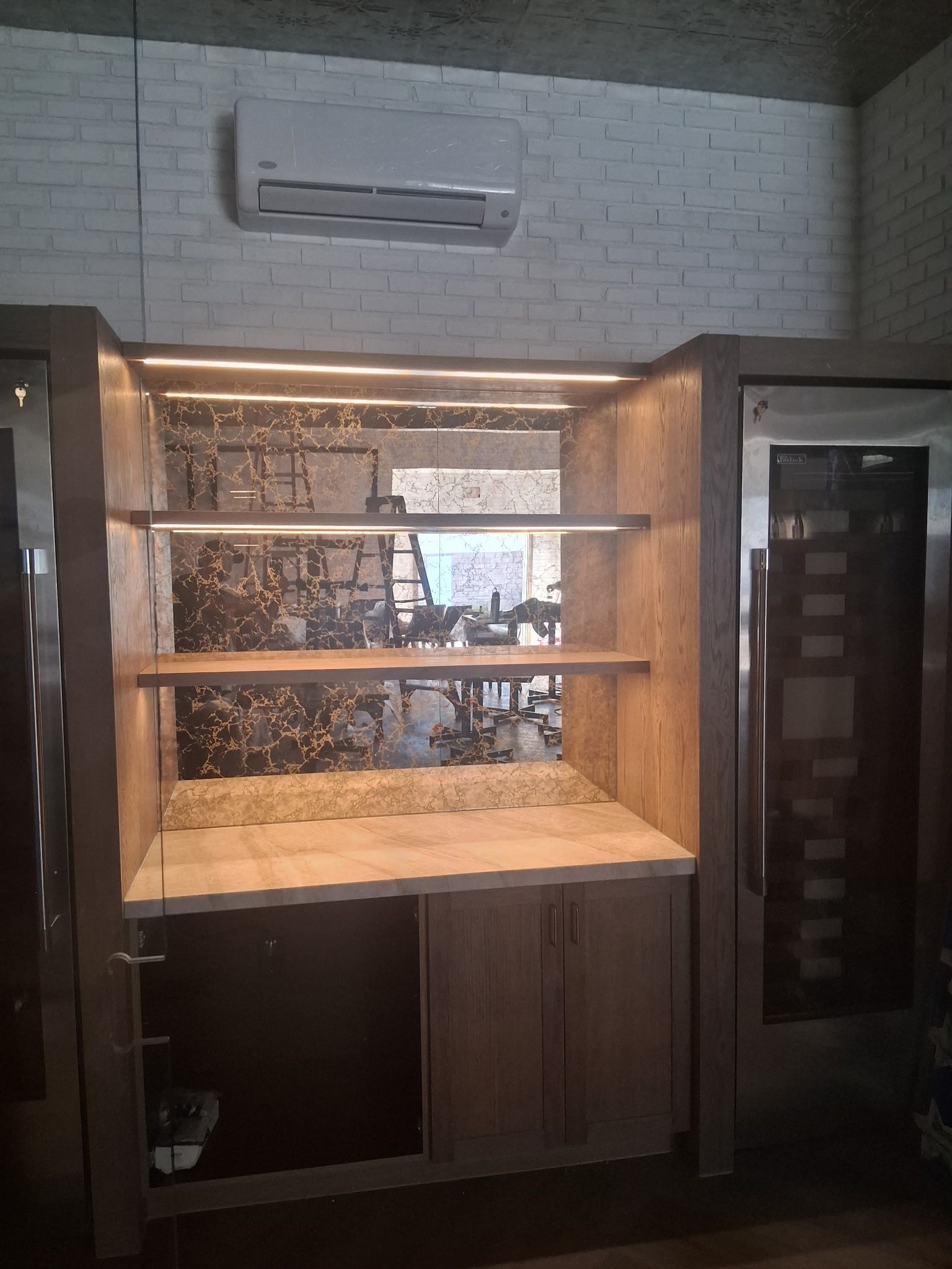Empty bakery display case with wooden shelves and warm lighting under an air conditioner