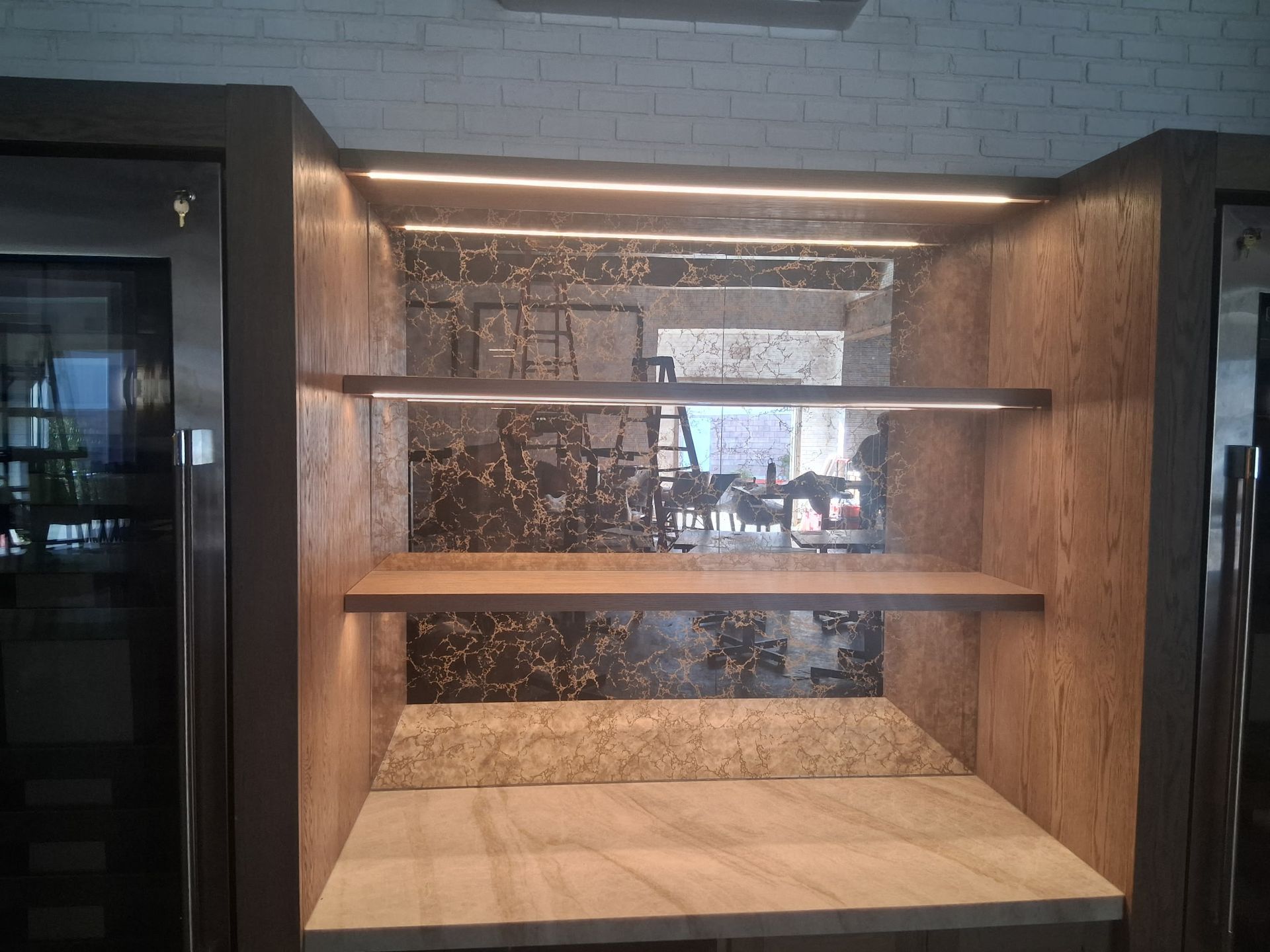 Empty built-in shelf alcove with warm wood panels and glass shelves in a modern interior.