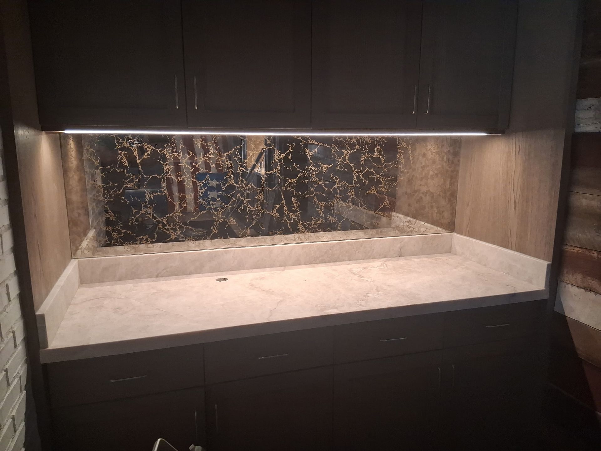 Built-in stone counter with dark cabinets and under-cabinet lighting in a kitchen nook
