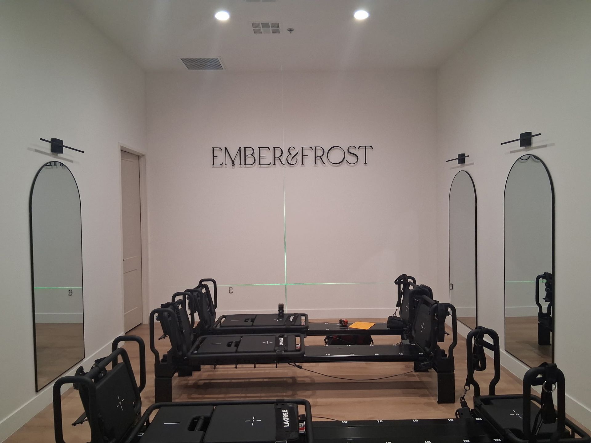 Elegant Pilates studio with reformer machines, mirrored walls, and the word “EMBERFROST” on the back wall