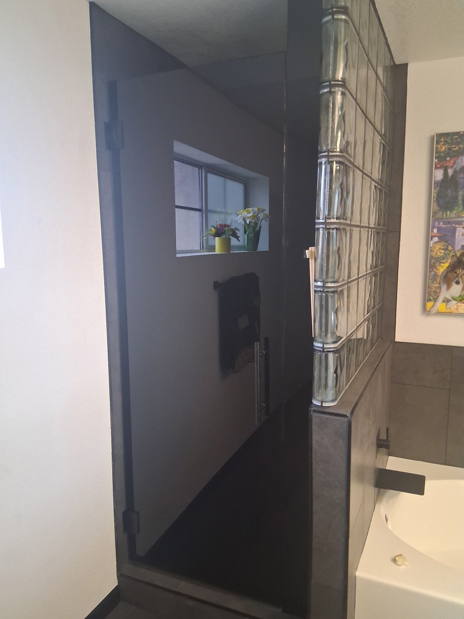 Hallway with a dark accent wall, small window shelf, and metal decorative mirror beside a sink.