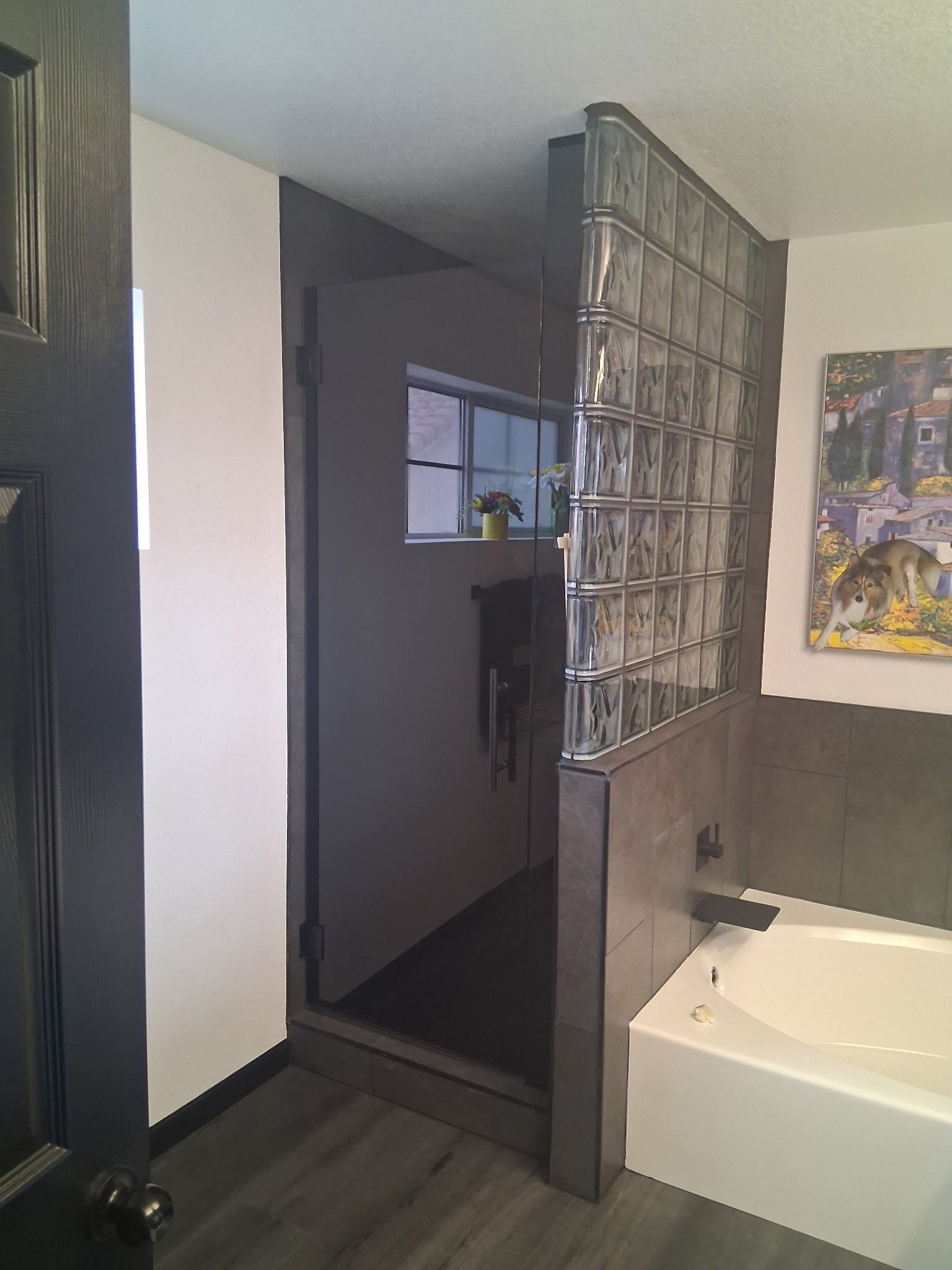 Bathroom with a white tub, glass block wall, and dark hallway entry beside it