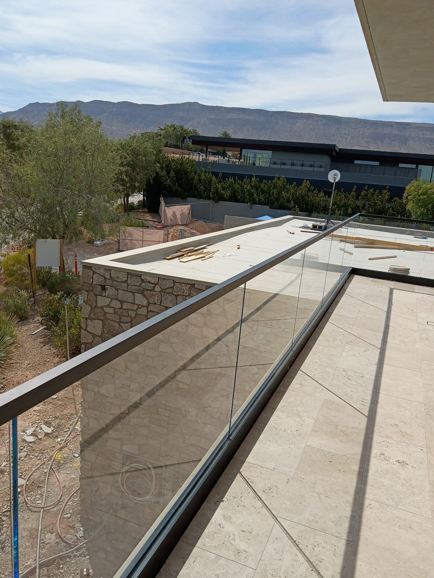 Outdoor ramp with metal handrails leading to a building, with desert landscaping and mountains in the distance
