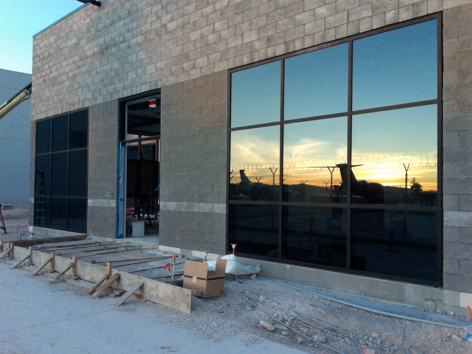 Storefront under construction with large reflective windows at sunset