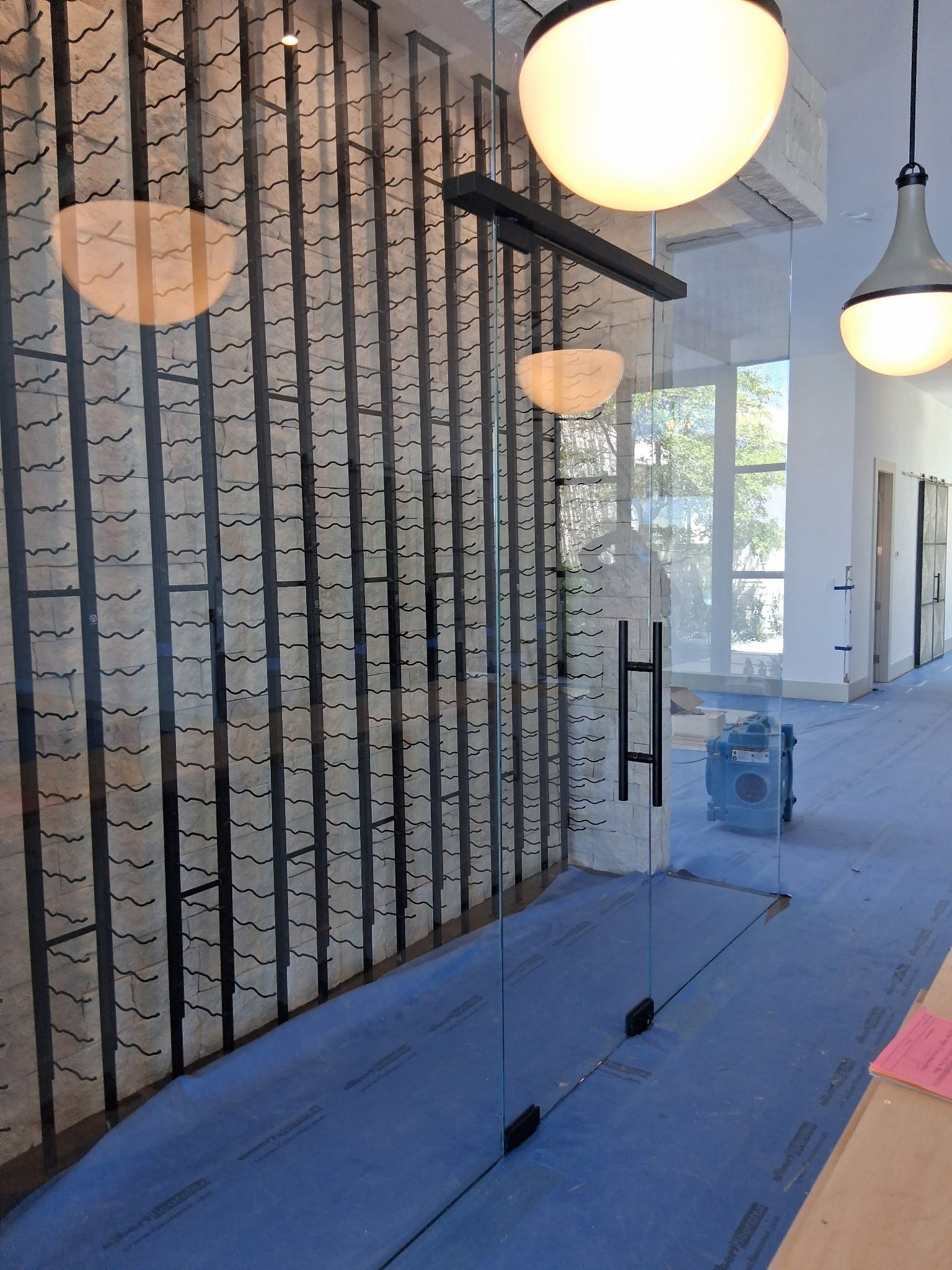 Modern hallway with exposed brick, hanging globe lights, blue carpet, and large windows