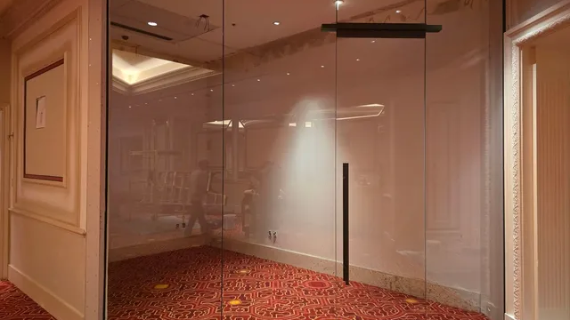 Empty modern glass office room with beige walls and red patterned carpet