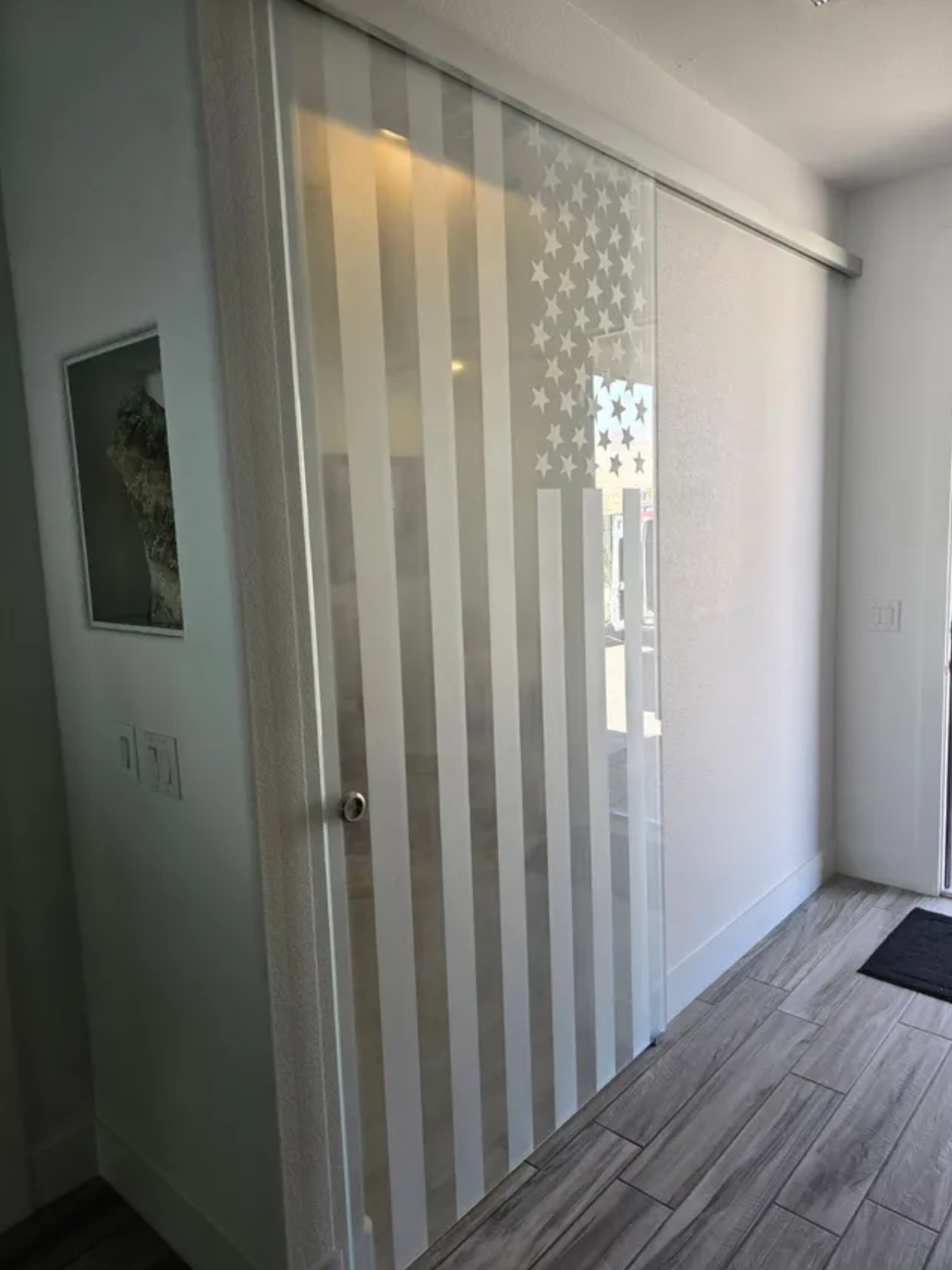 Modern glass sliding door with vertical frosted stripes in a bright hallway