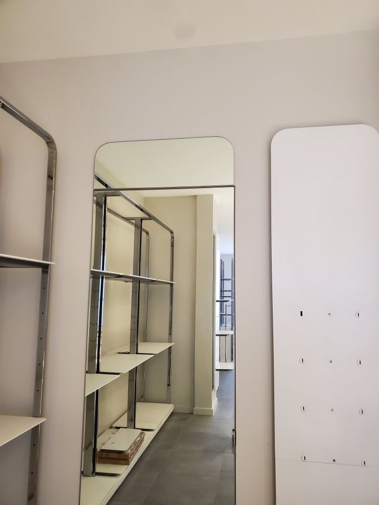Empty store interior with metal shelving and a tall mirror leaning against the wall