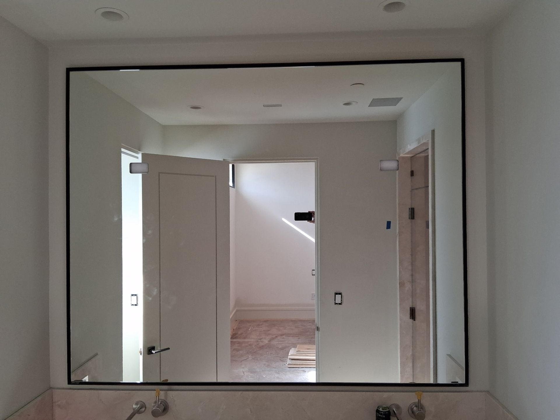 Indoor hallway seen through a large wall opening, with open white doors and a staircase visible beyond.