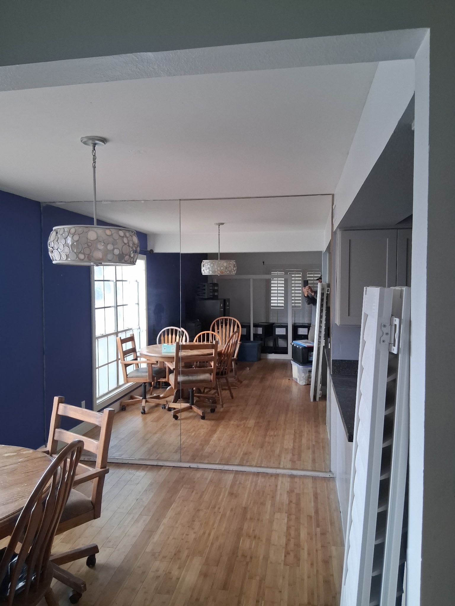 Dining room with wooden table and chairs, blue walls, and large windows letting in natural light.
