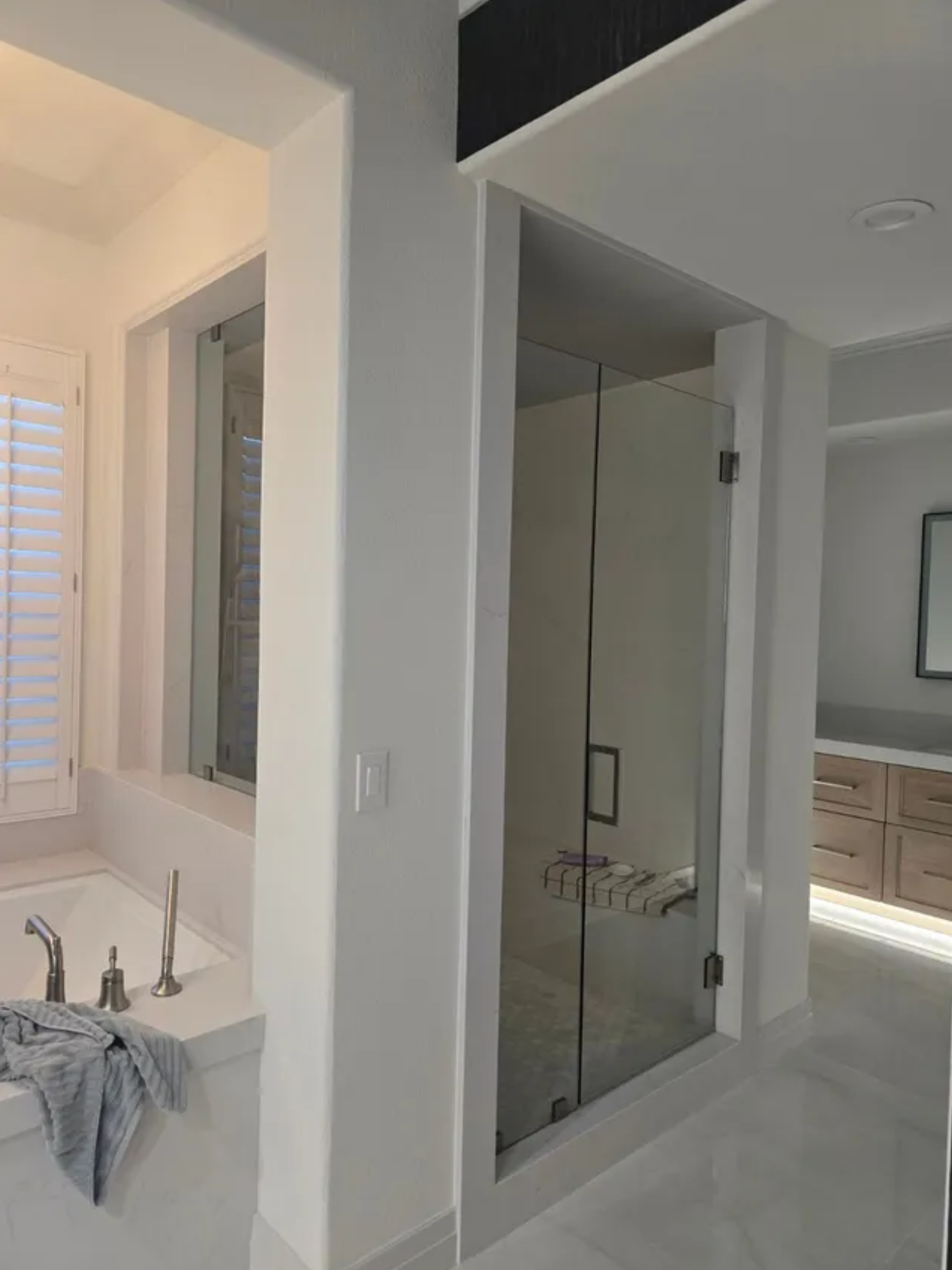 Modern bathroom with a glass shower, double vanity, and bathtub beside a window