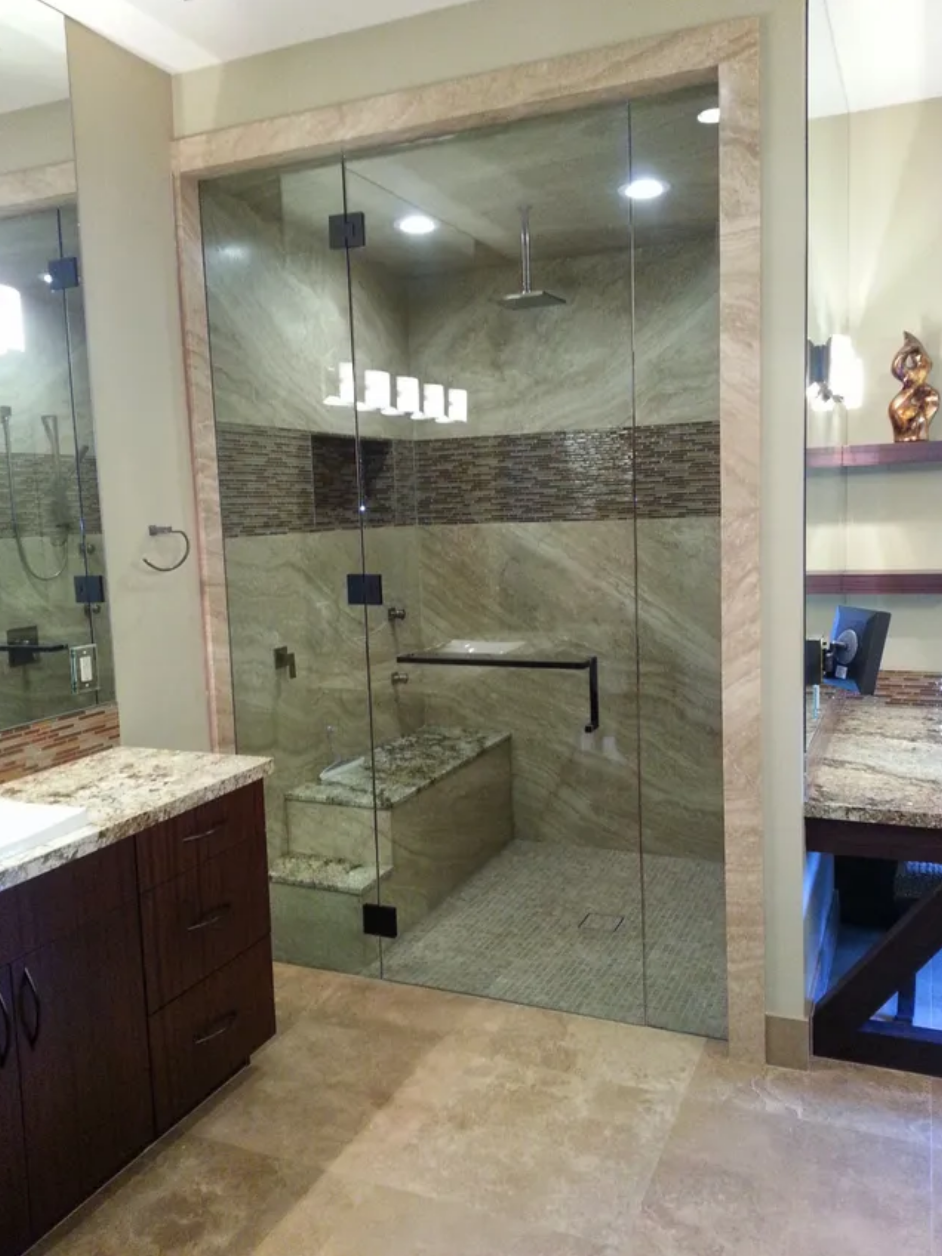 Modern bathroom with glass shower enclosure, beige tile, and granite countertop vanity