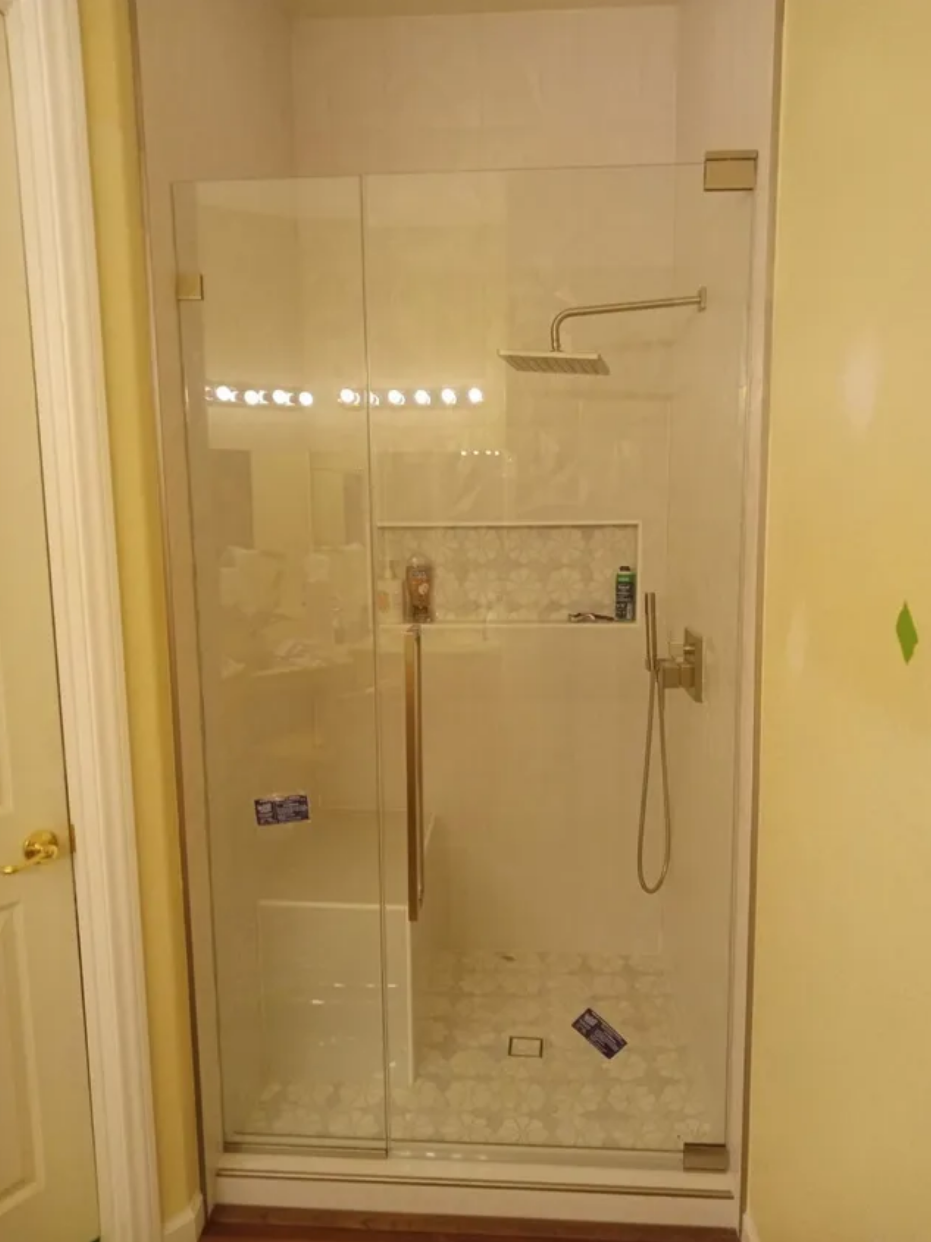 Glass walk-in shower with chrome fixtures and tiled walls in a beige bathroom