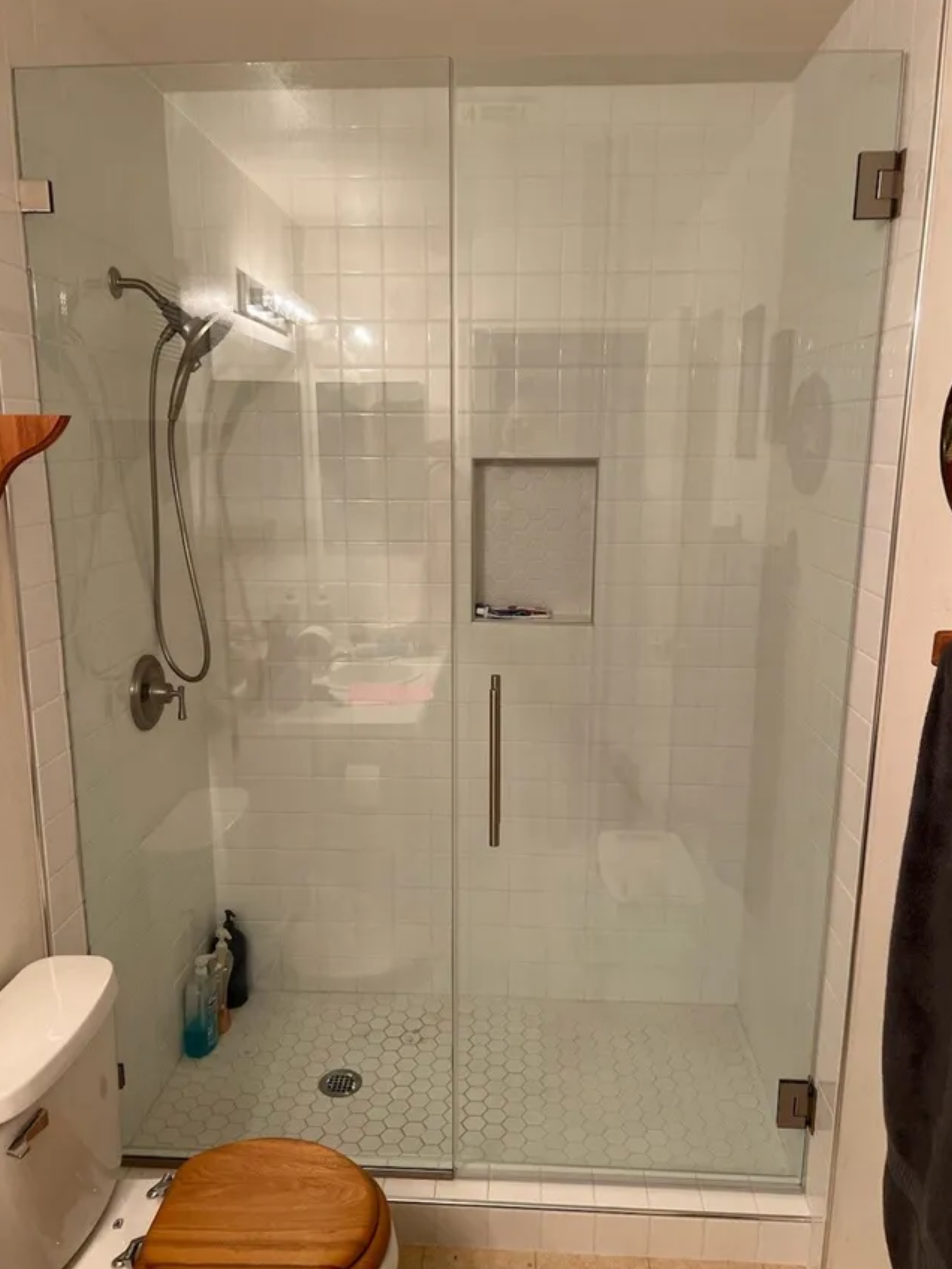 Glass walk-in shower with chrome fixtures, tiled walls, and a built-in niche in a bathroom