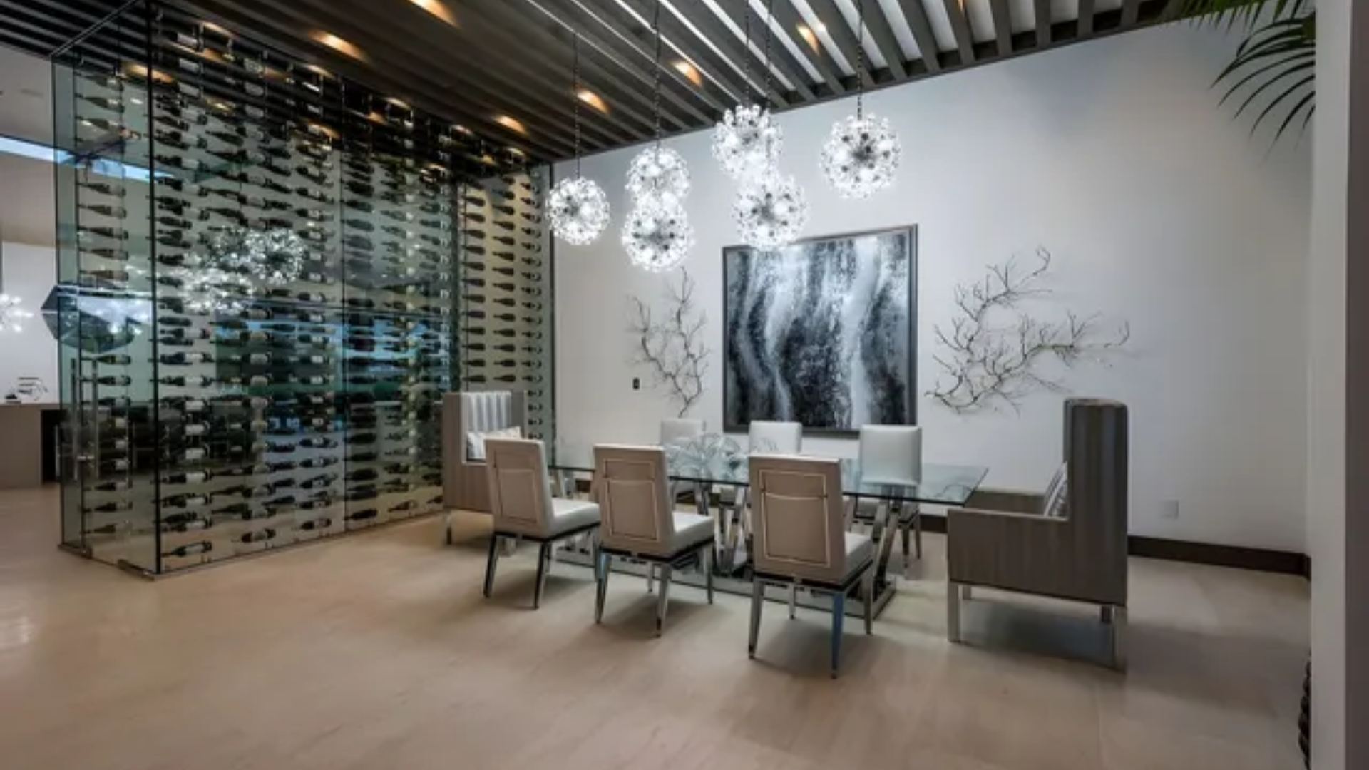 Modern dining room with glass table, beige chairs, wall art, and pendant lights