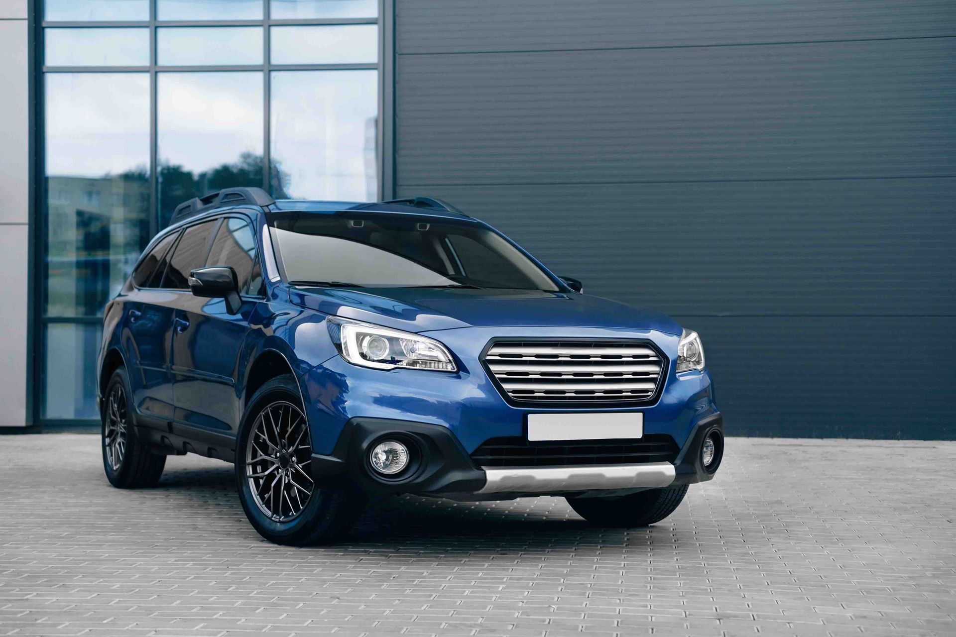 A blue suv is parked in front of a building.