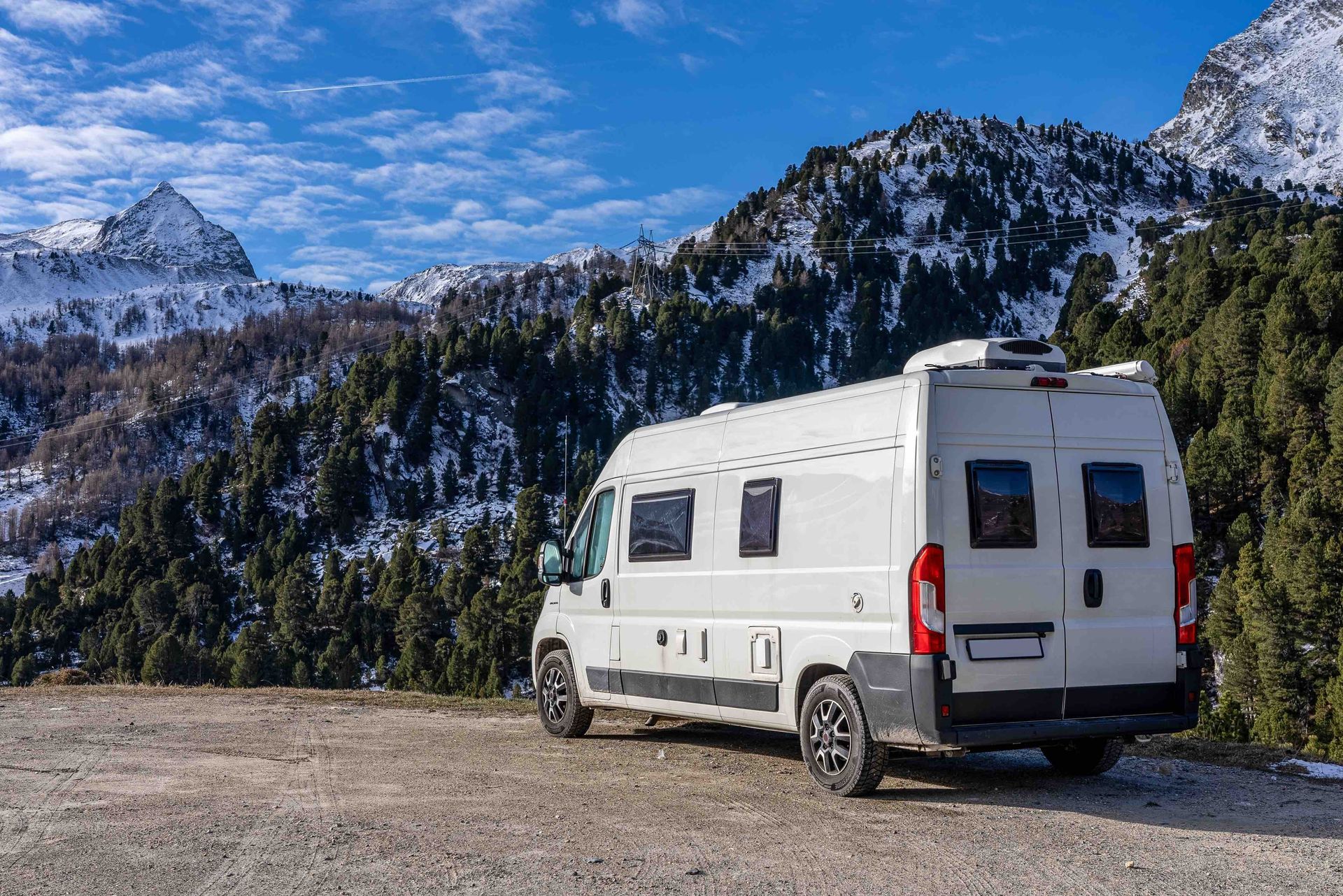 A white rv is parked in front of a snowy mountain.