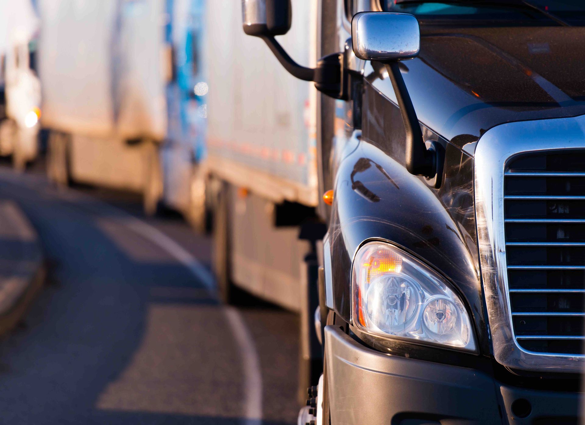 A row of semi trucks are driving down a highway.