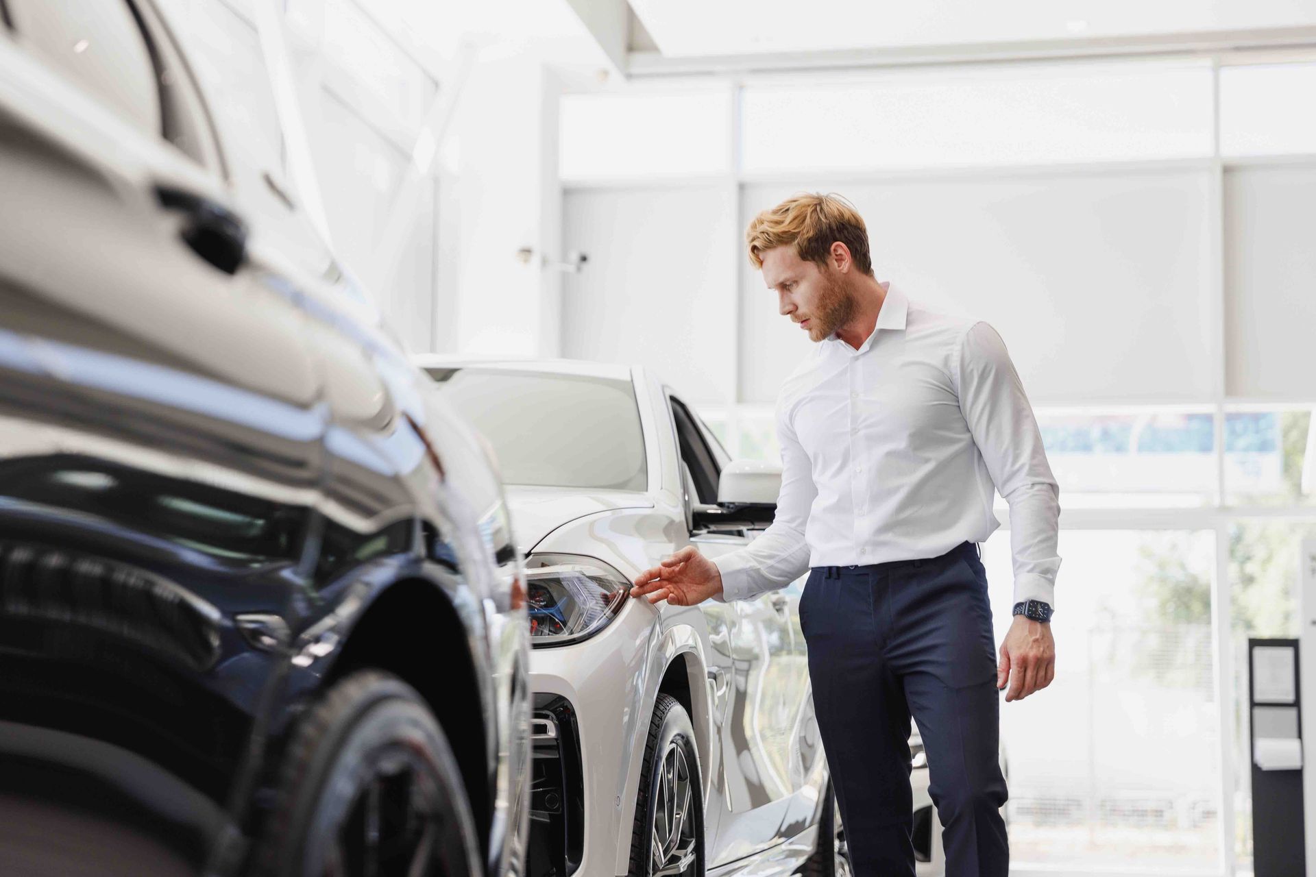A man is looking at a car in a showroom.