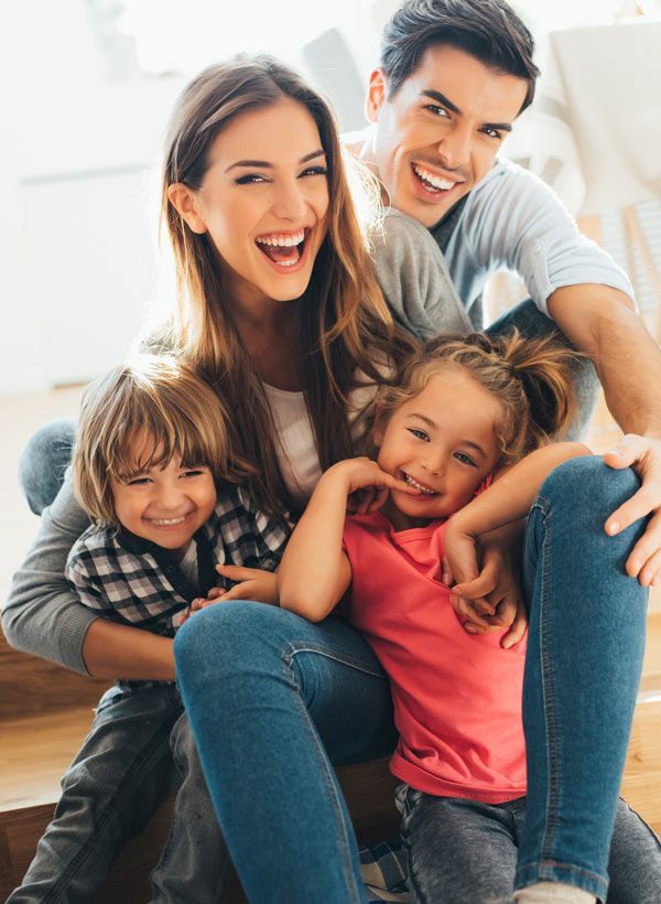 Smiling family sitting closely together on a couch in a bright living room