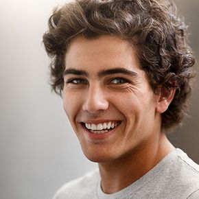 Smiling young man with curly hair in a light gray shirt