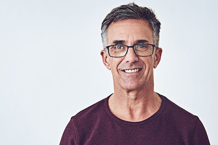 Smiling man with glasses in a maroon shirt