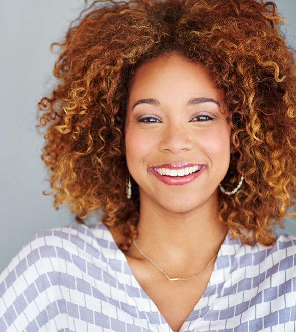 Smiling person with curly hair in a striped top 