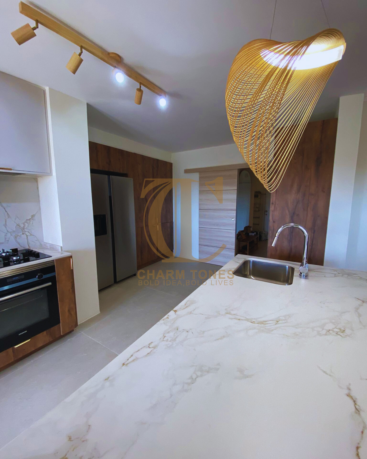 Cozinha moderna com bancada de mármore, eletrodomésticos de aço inoxidável e um exclusivo pendente dourado.