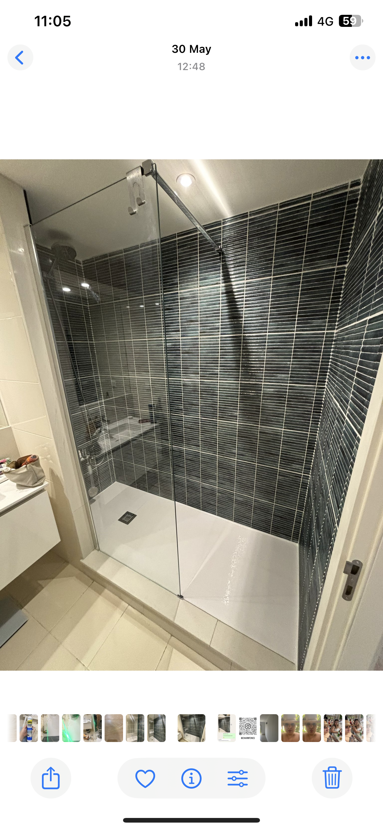 Chuveiro moderno com parede de azulejos ondulados em preto e branco, box de vidro e base de chuveiro branca.