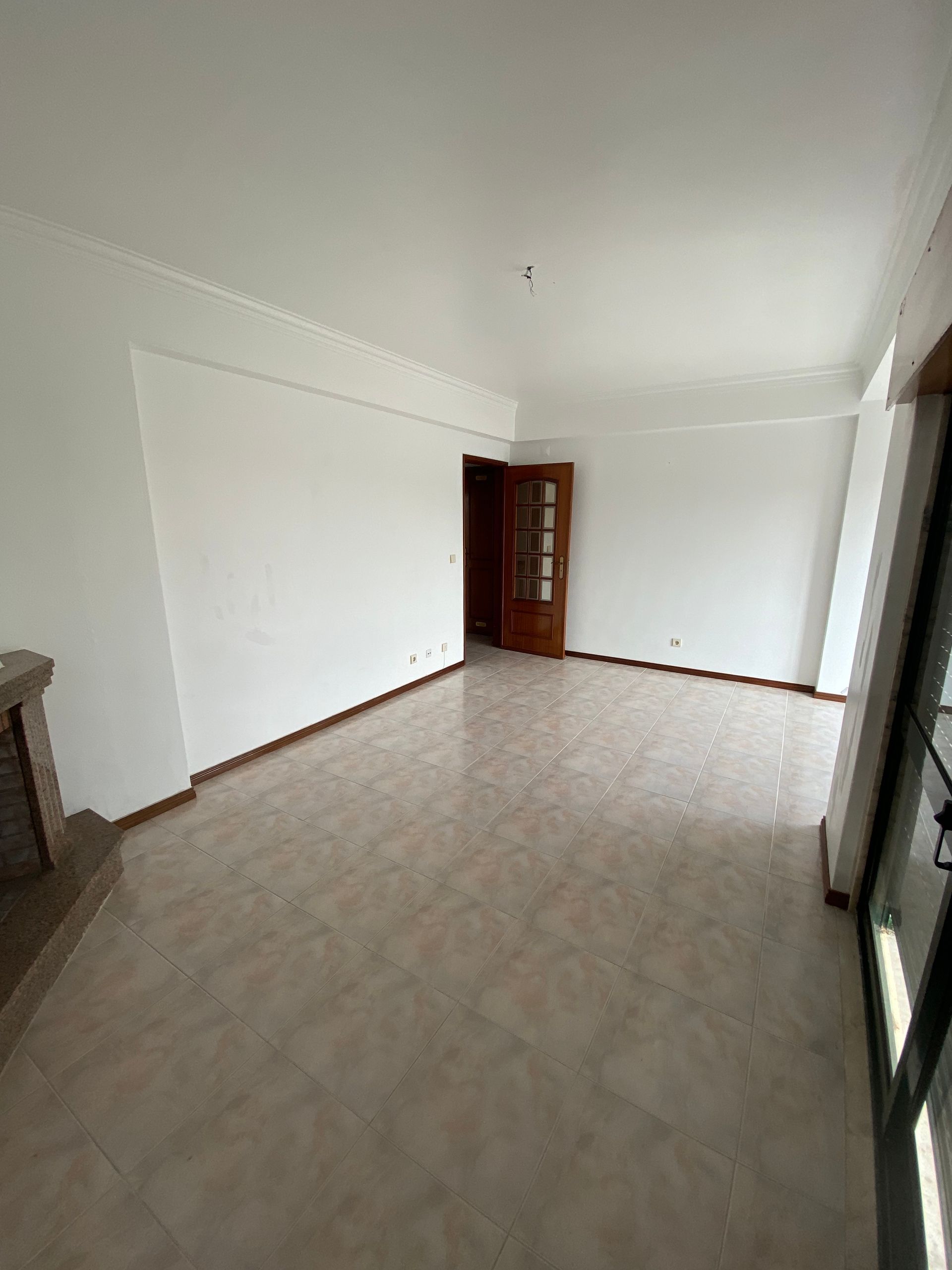 Uma sala de estar vazia com paredes brancas e uma lareira.