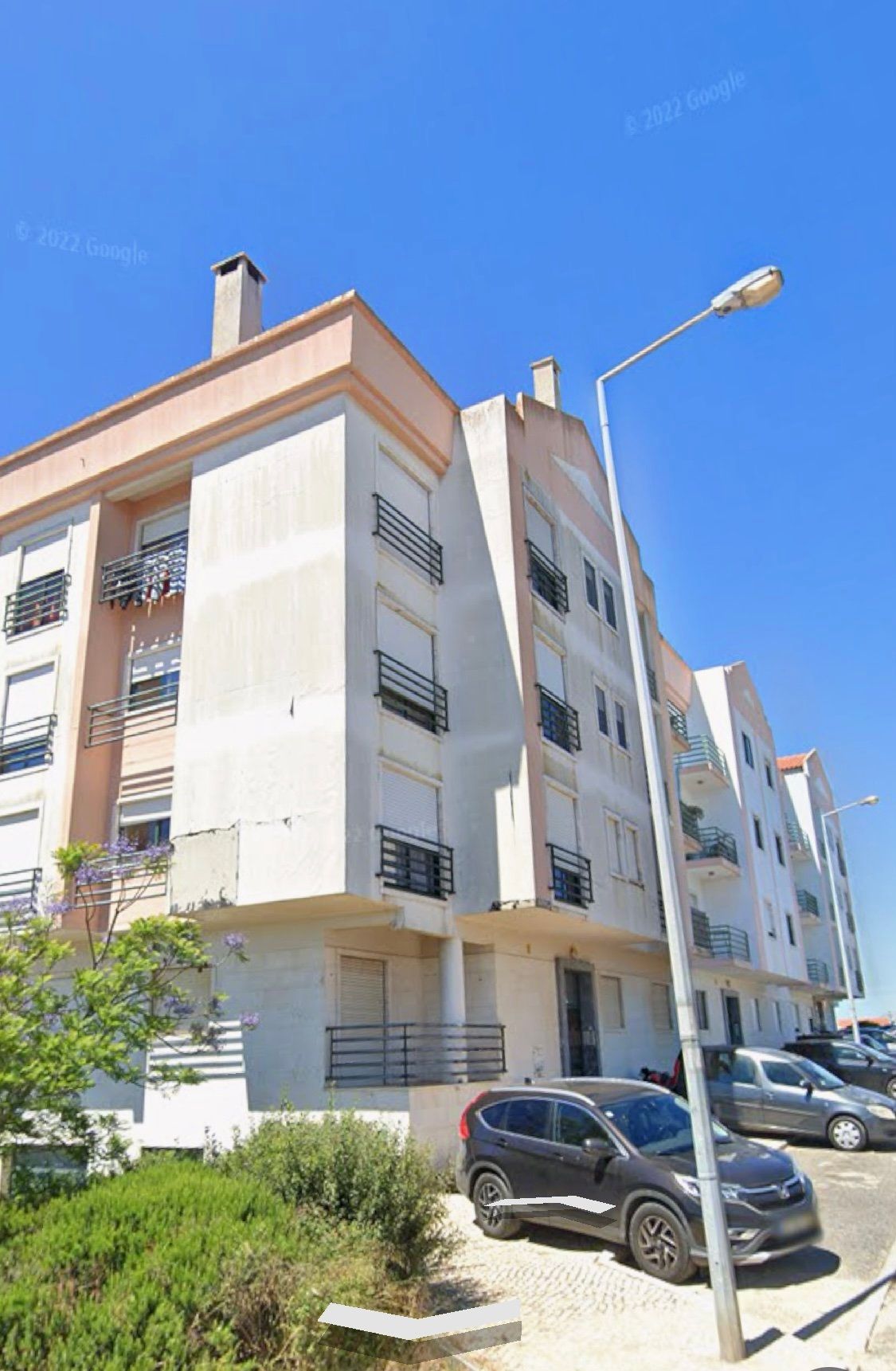Um carro está estacionado em frente a um grande prédio de apartamentos.