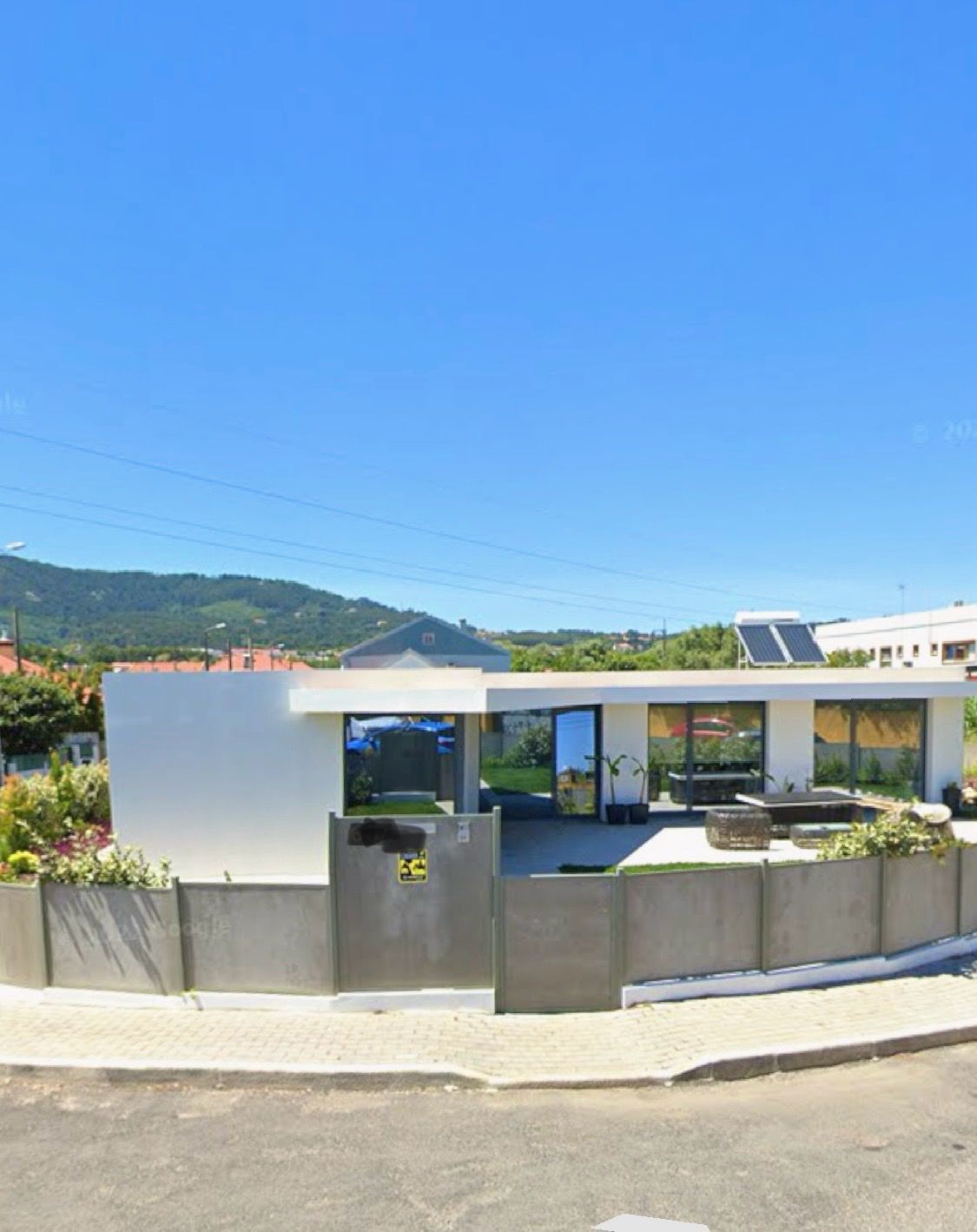 Uma casa branca com uma cerca ao redor e montanhas ao fundo