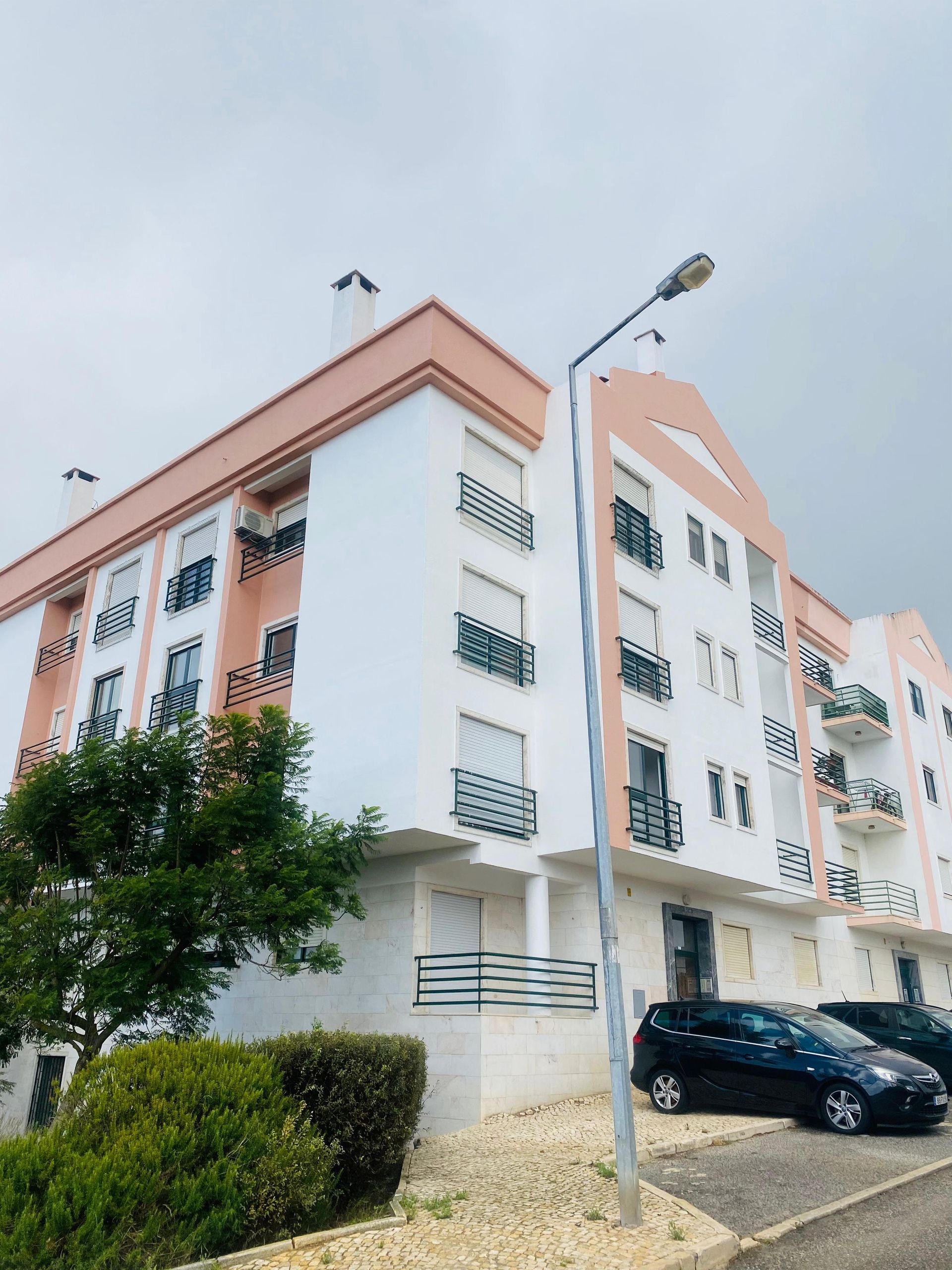 Um grande prédio de apartamentos com carros estacionados na frente