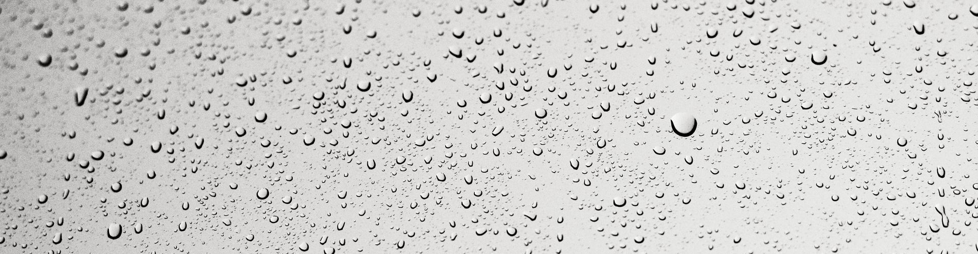 A black and white photo of rain drops on a window.