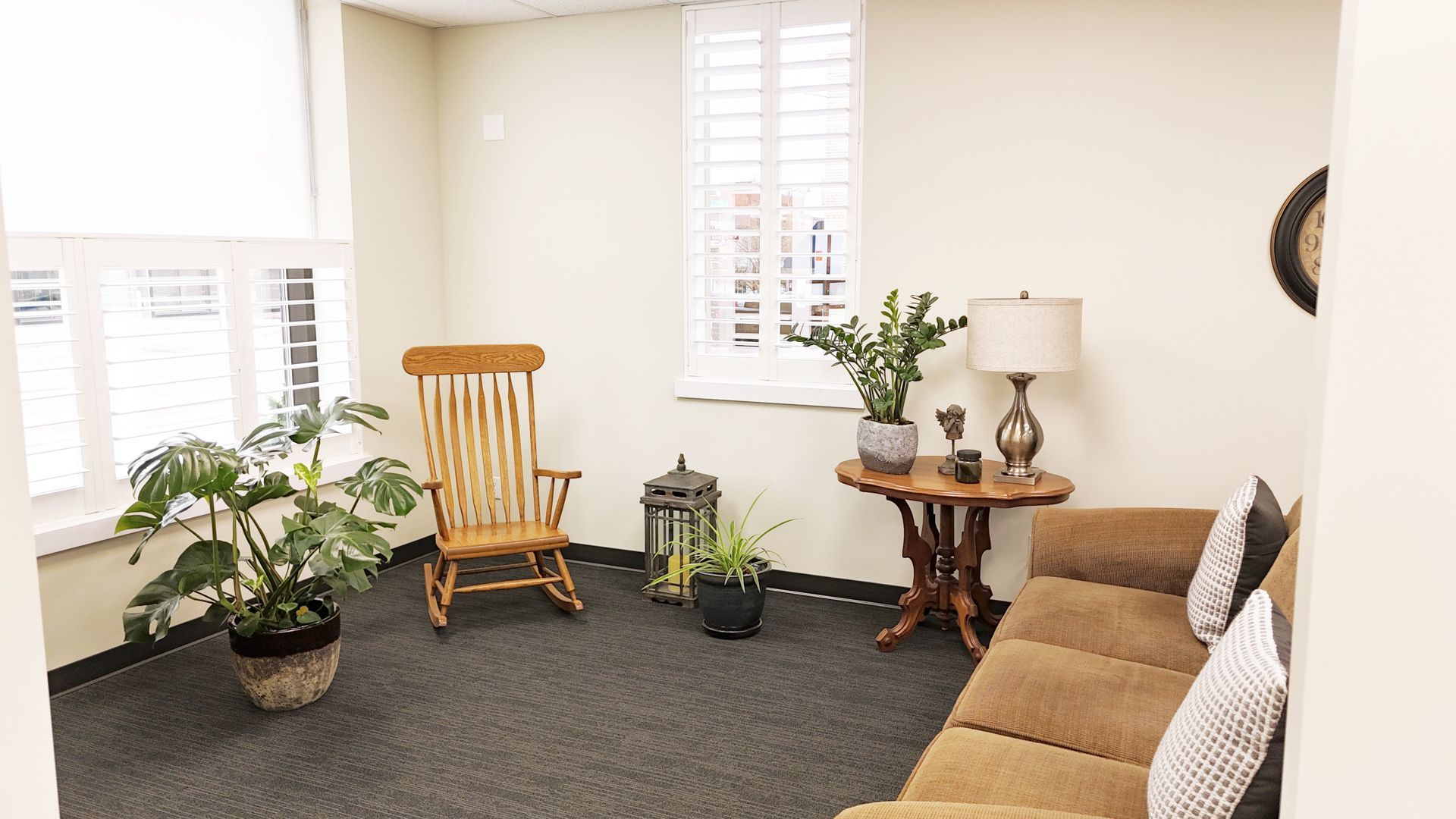 A living room with a couch , chair , table and potted plants.
