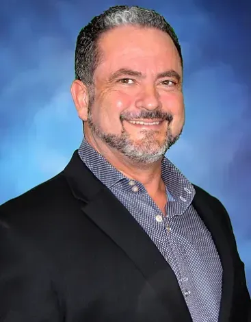 A man with a beard is wearing a suit and smiling for the camera.