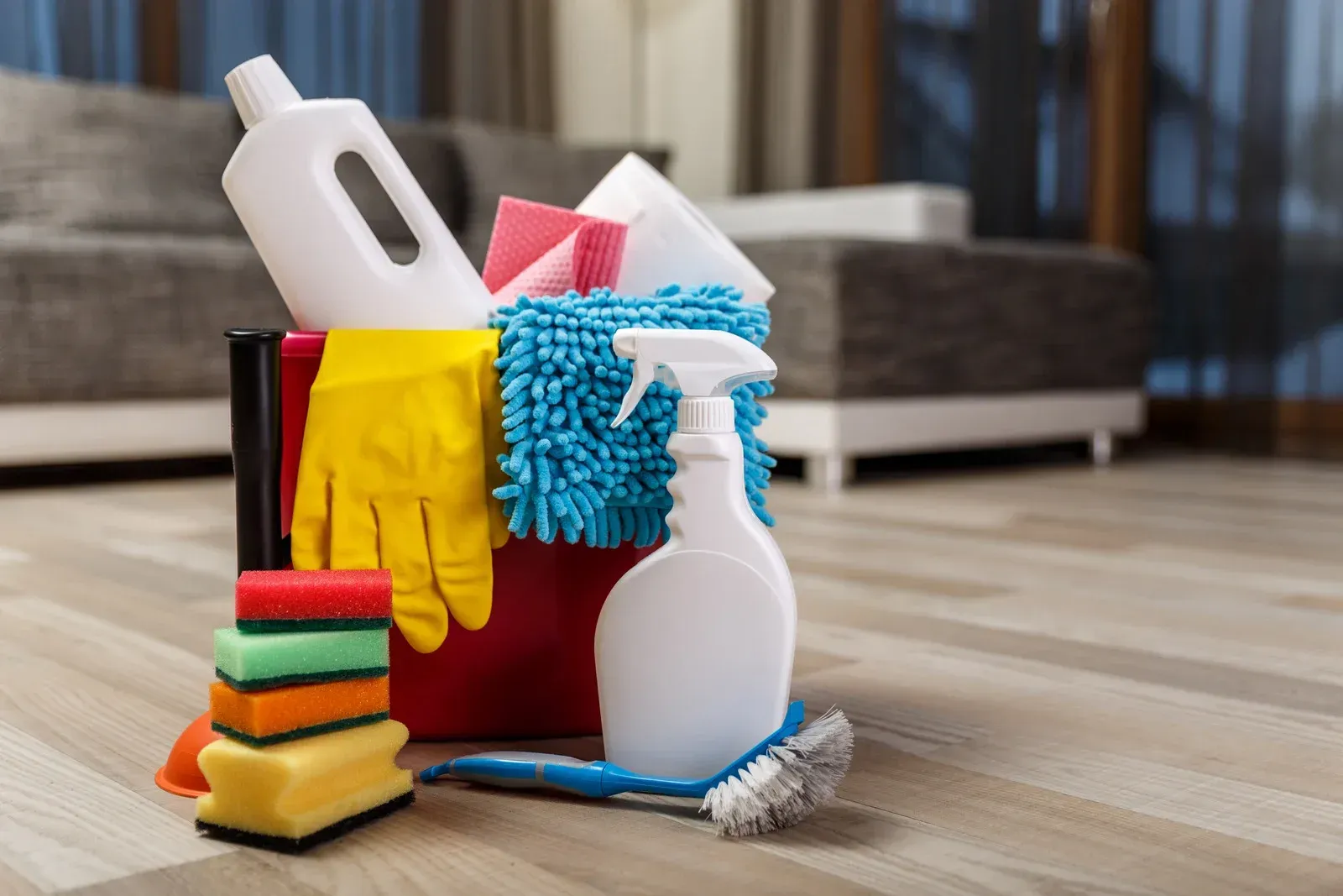 A bucket filled with cleaning supplies is sitting on the floor in a living room.
